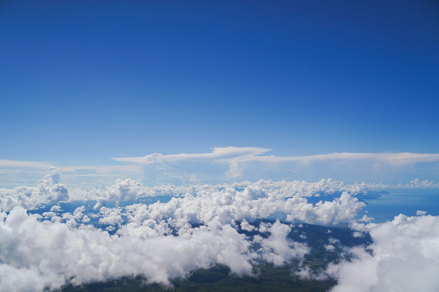 A landscape featuring a blue sky with fluffy white clouds