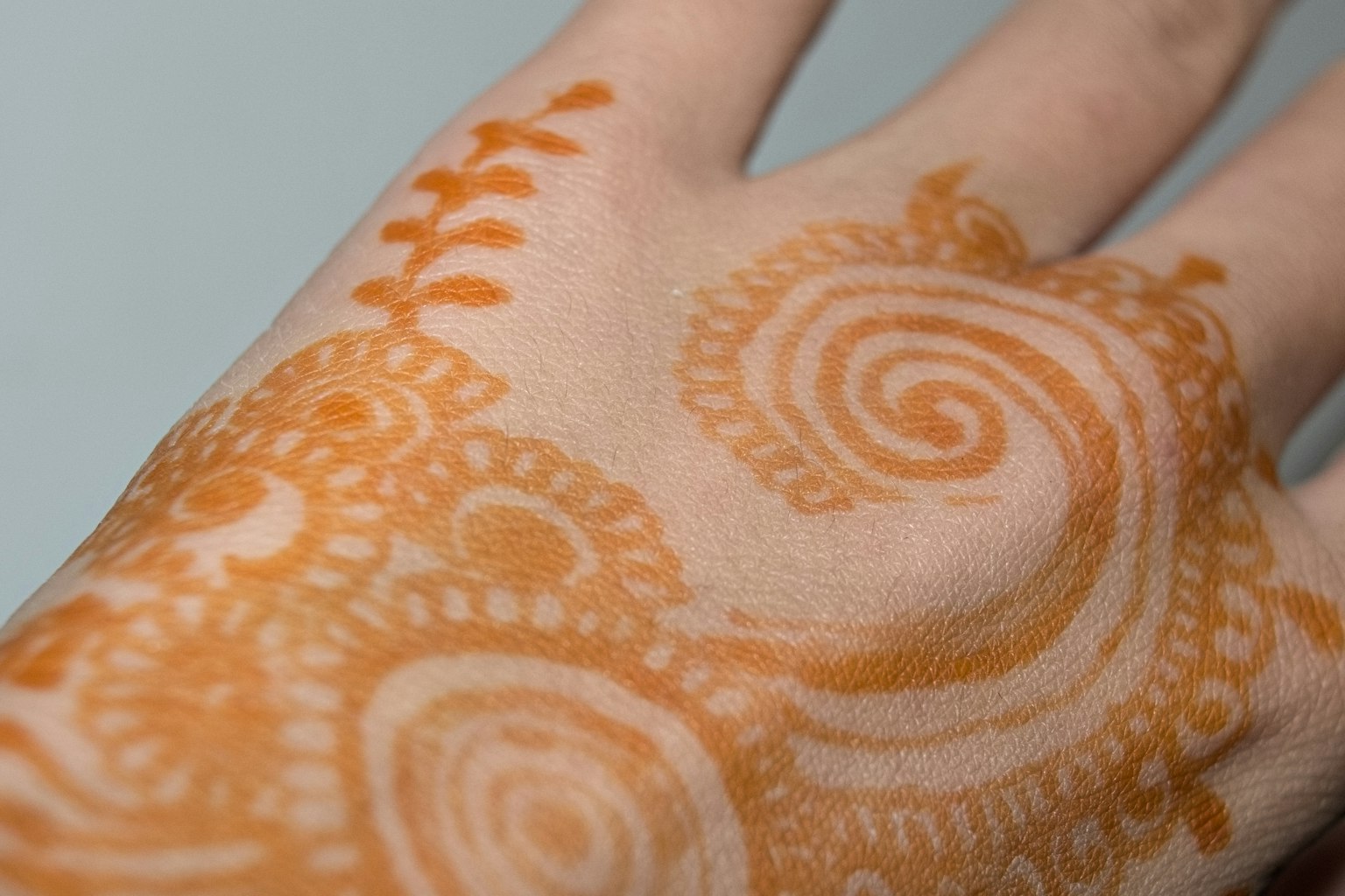 Detailed orange henna design on a palm showcasing intricate patterns