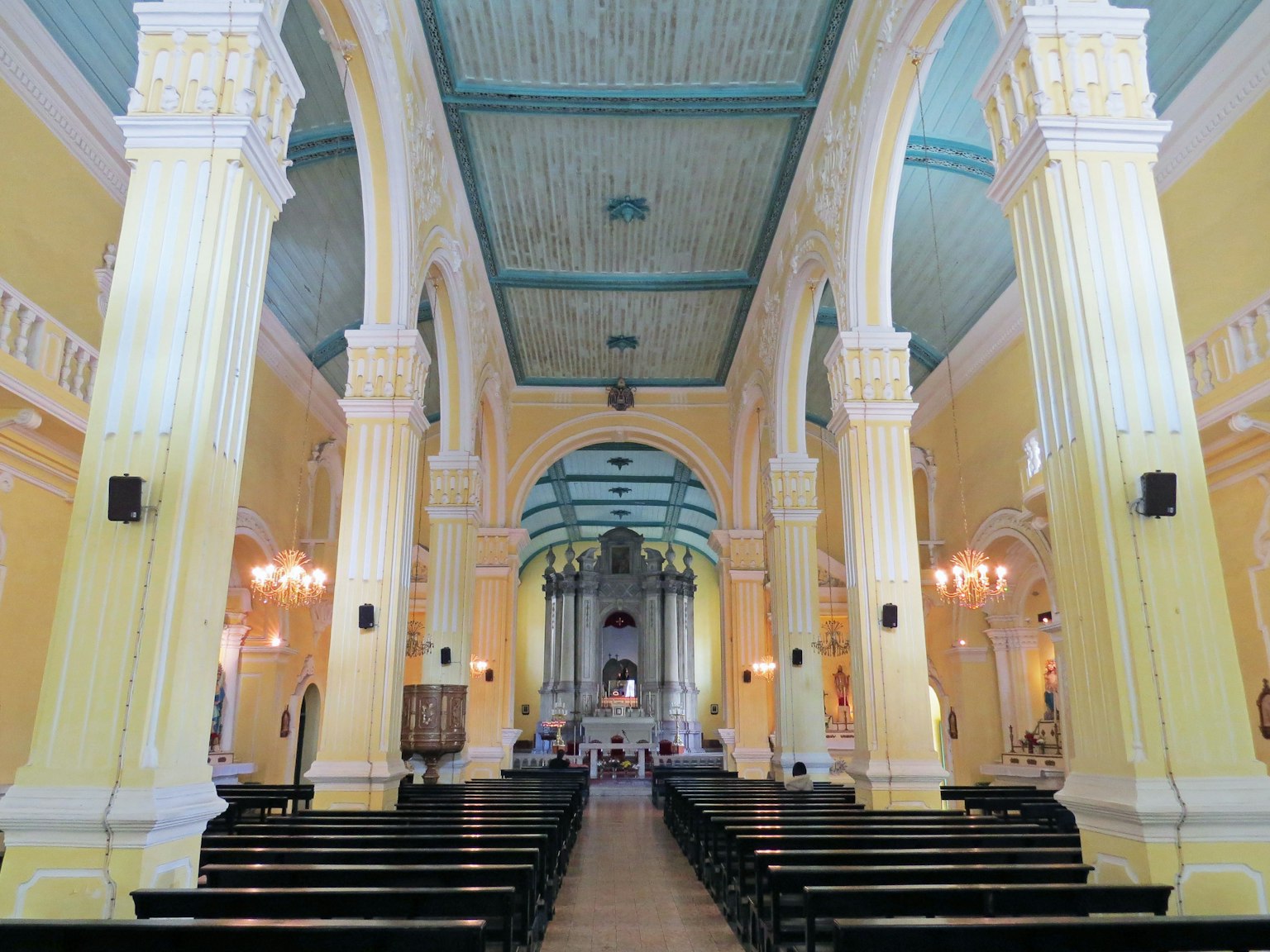 Interior view of a church featuring bright yellow walls and a blue ceiling
