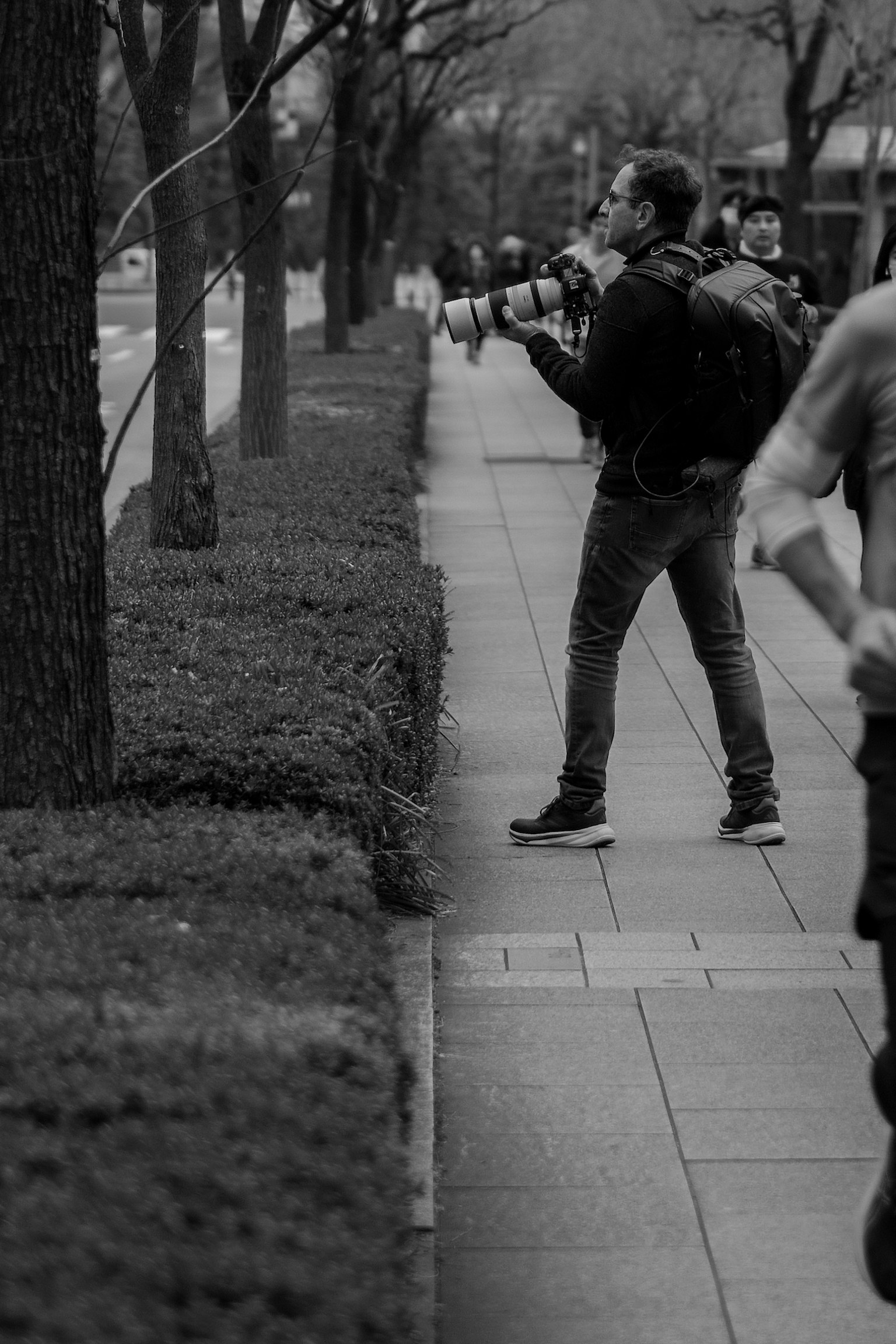 Man taking photos with a camera on a city sidewalk