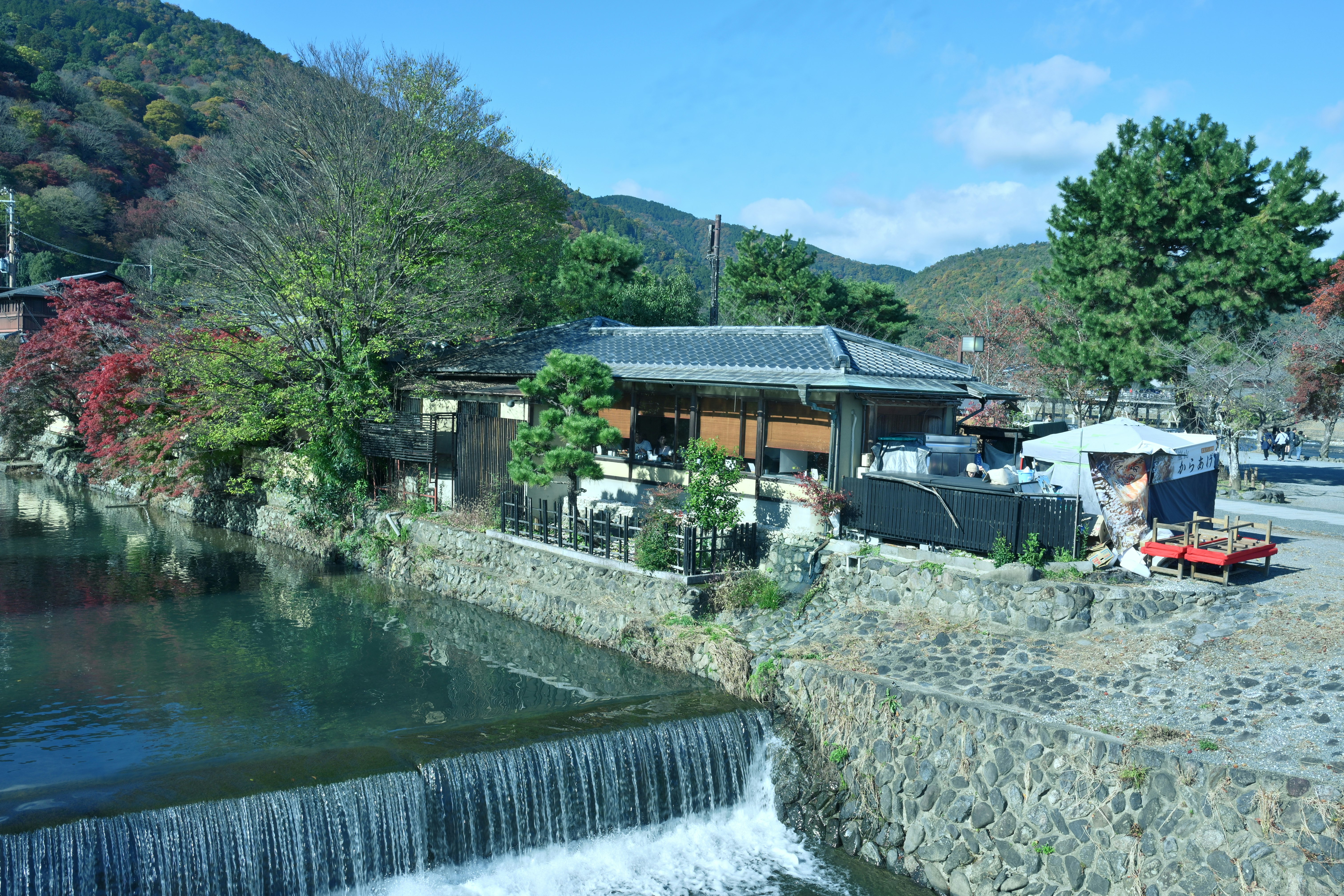 川沿いの石積みの護岸と小さな水車小屋のある風景