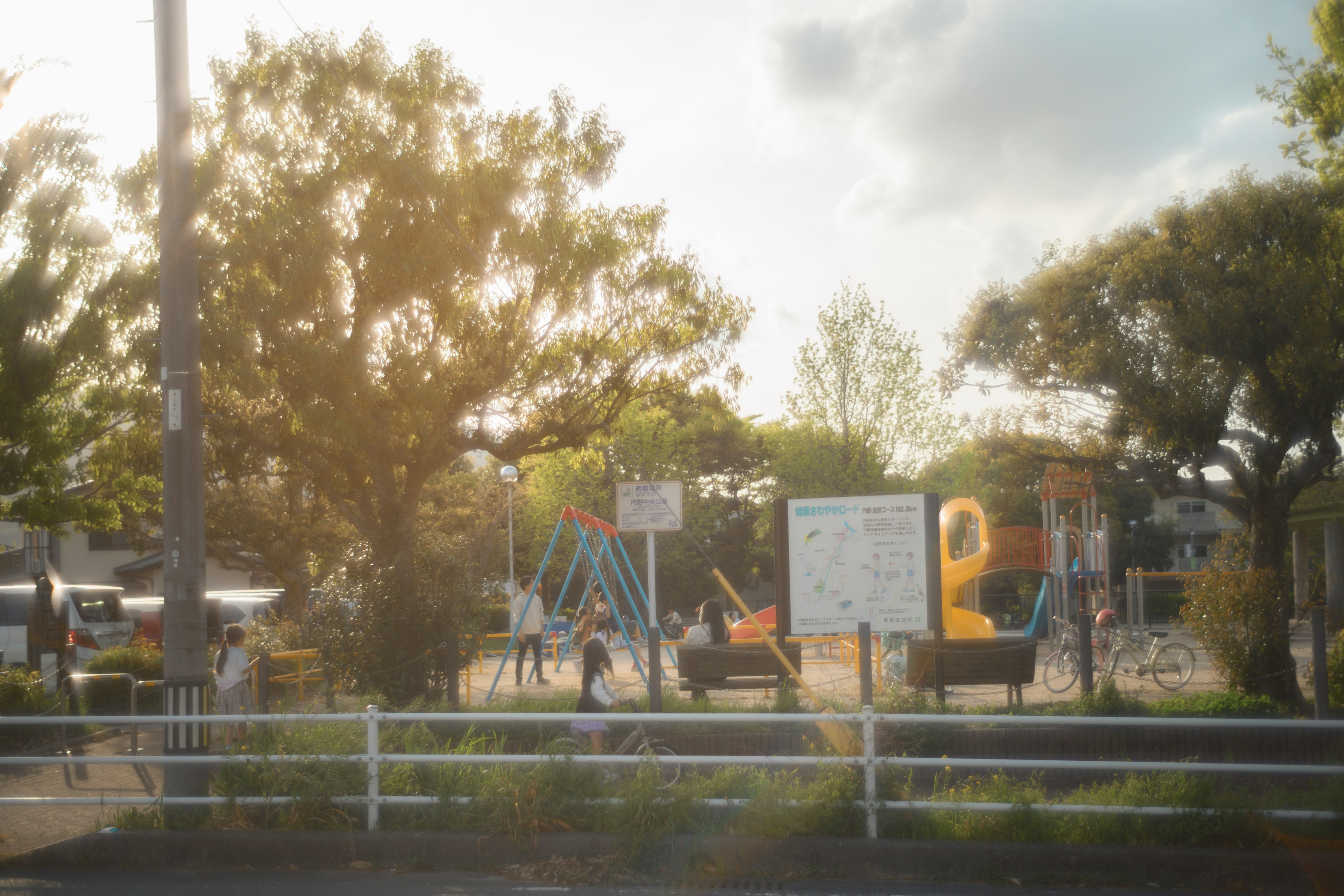 夕暮れの公園で遊具とベンチが並ぶ風景