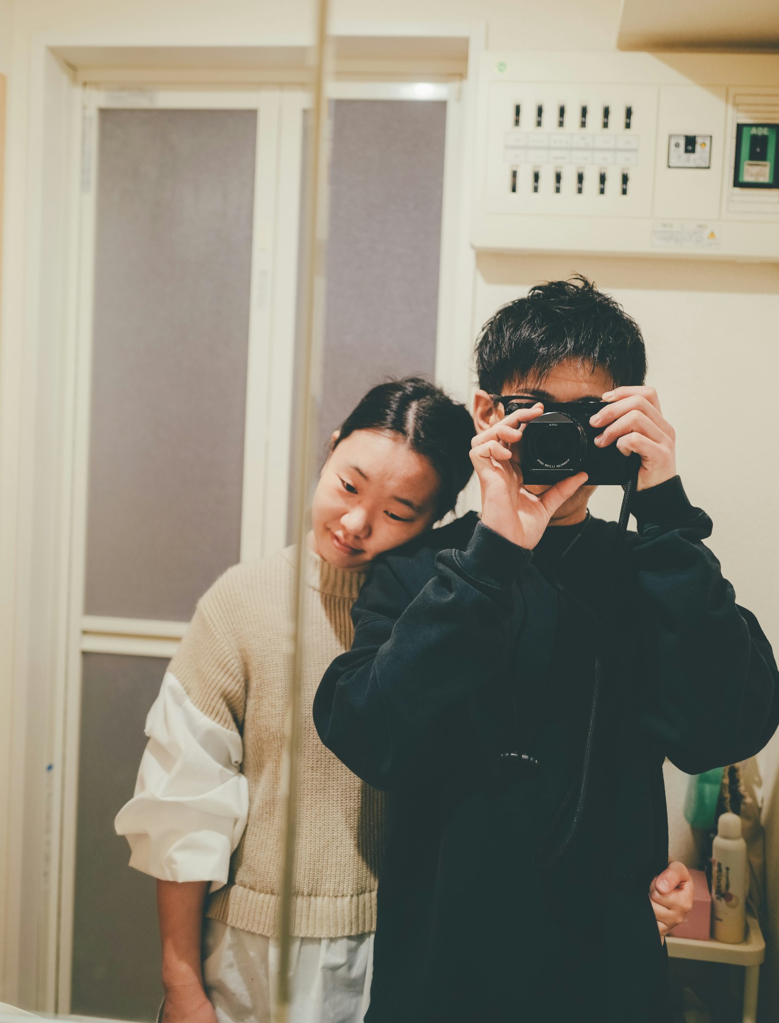 Due giovani che fanno un selfie davanti a uno specchio Uno tiene una macchina fotografica mentre l'altro si appoggia