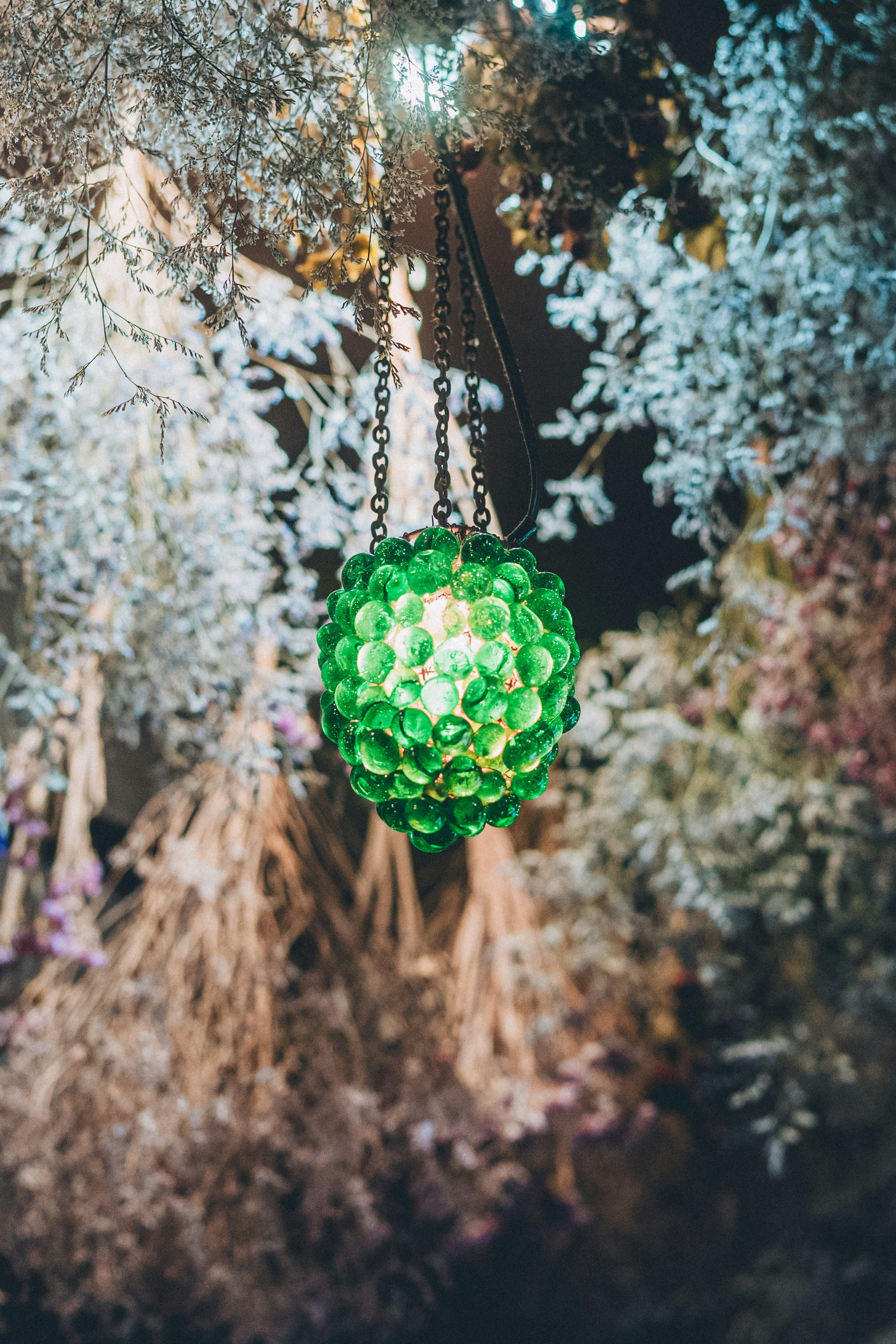 ornamento a forma di charm verde in vetro appeso ai rami