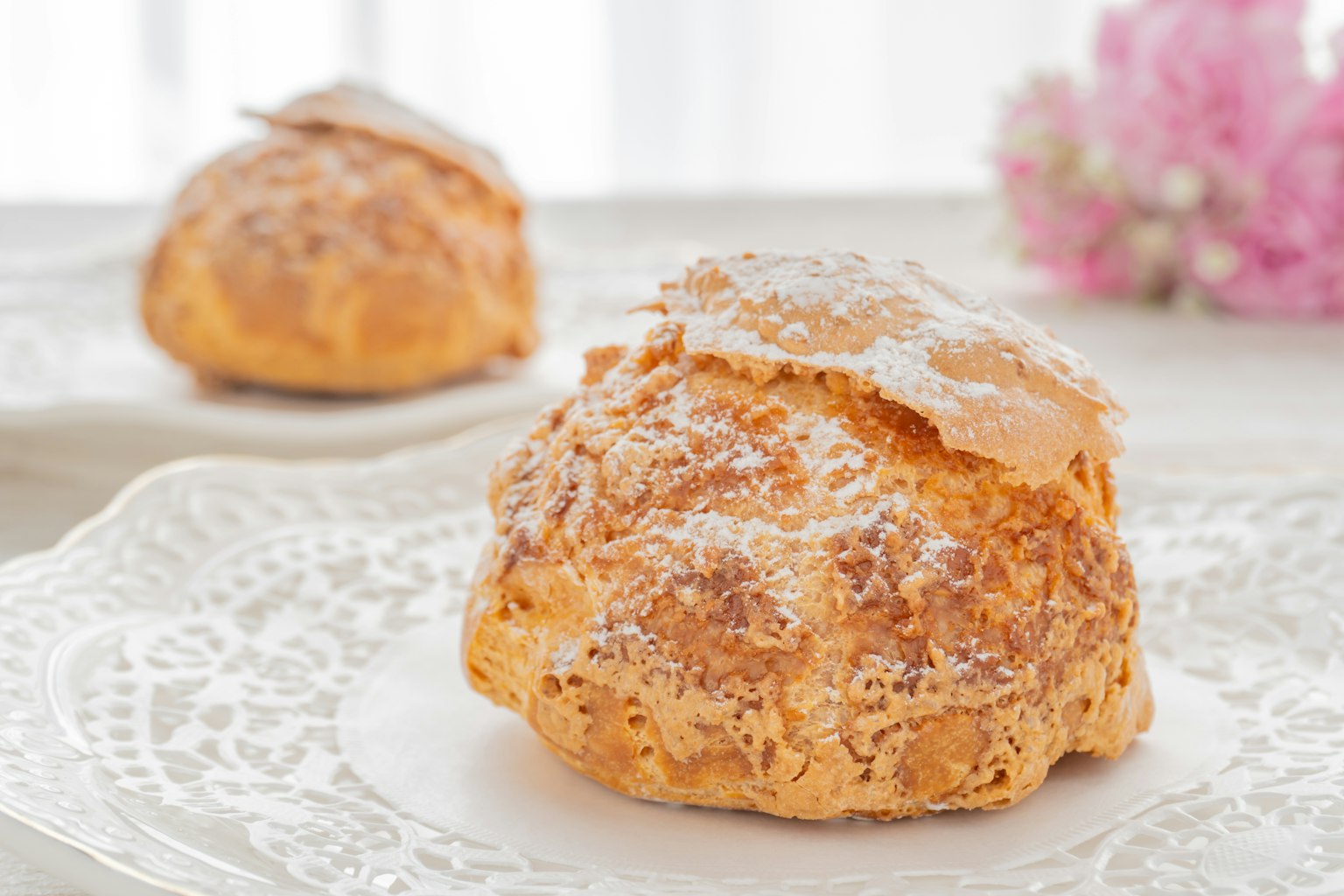 Pâtisserie à la crème sur une assiette blanche avec des fleurs en arrière-plan
