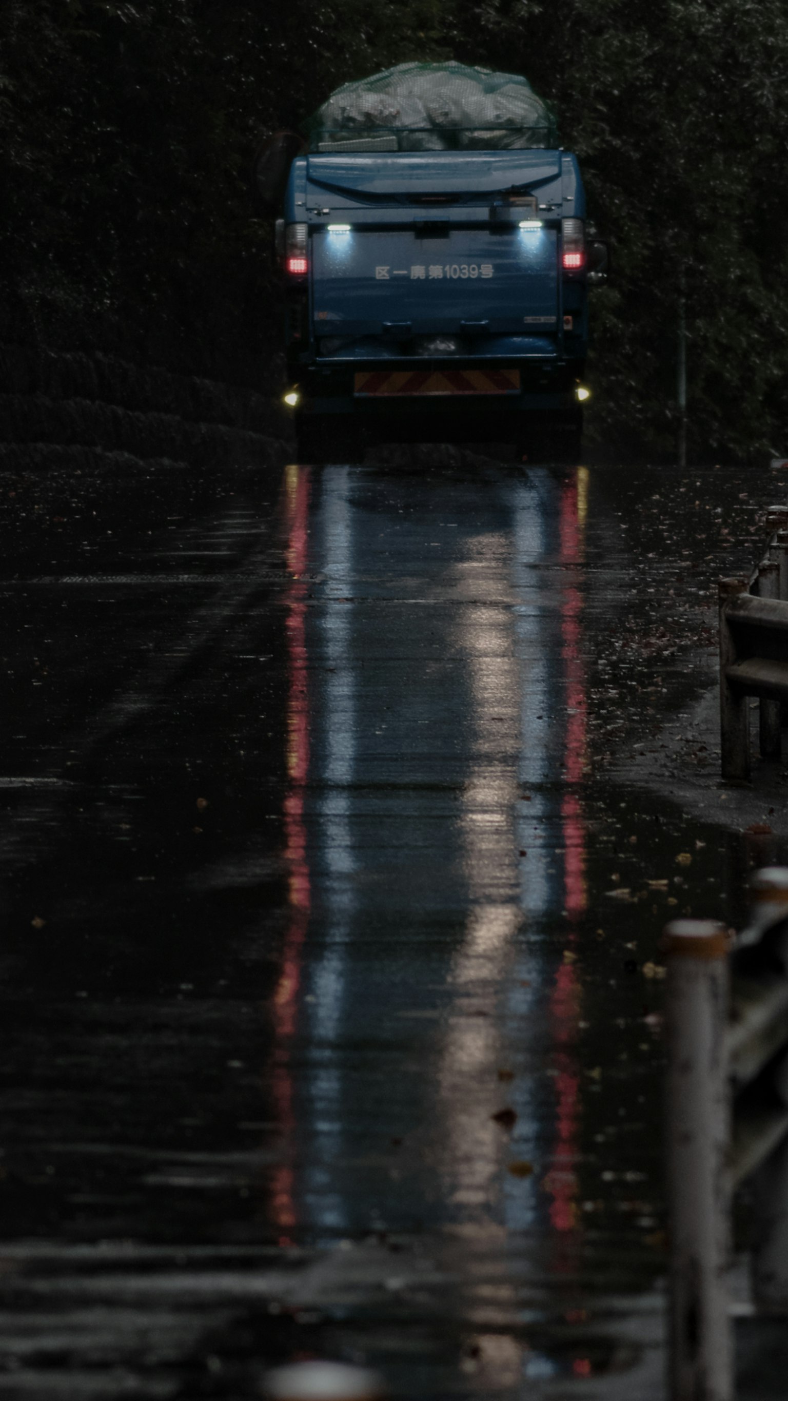 A blue vehicle driving on a wet road with reflections