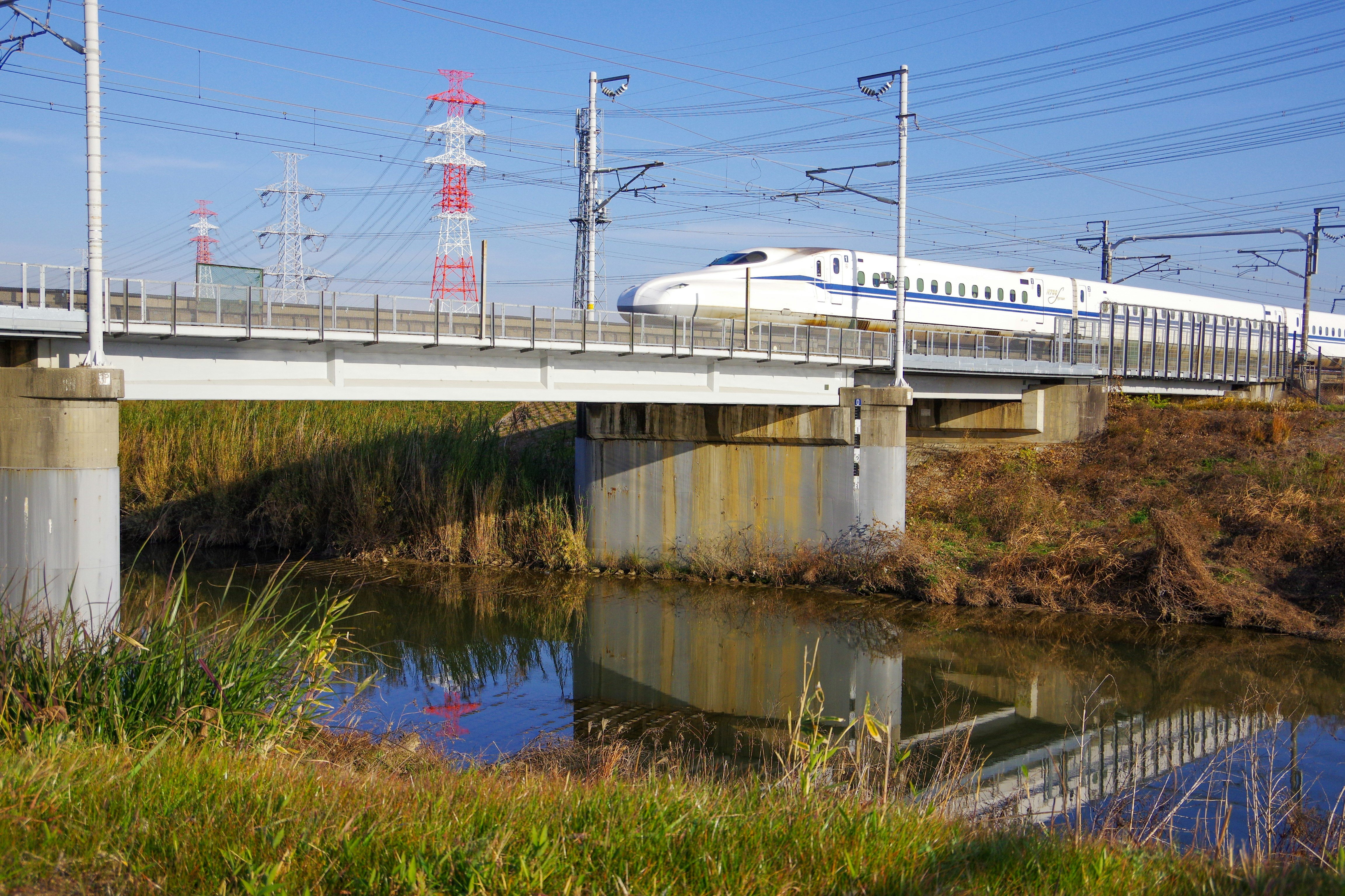 新幹線が川沿いの高架橋を走る風景