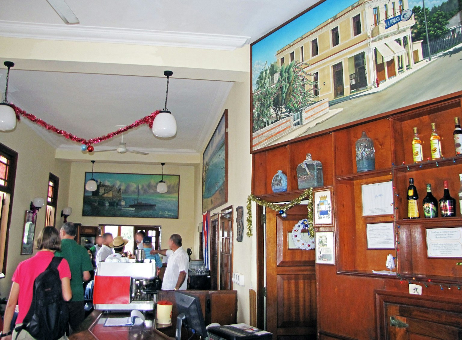 Interior de un bar retro con pinturas en la pared y botellas de licor visibles