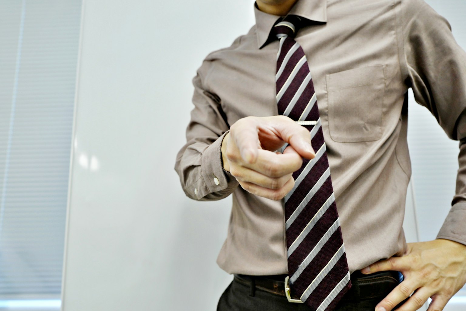 Man in a dress shirt and tie pointing with his finger