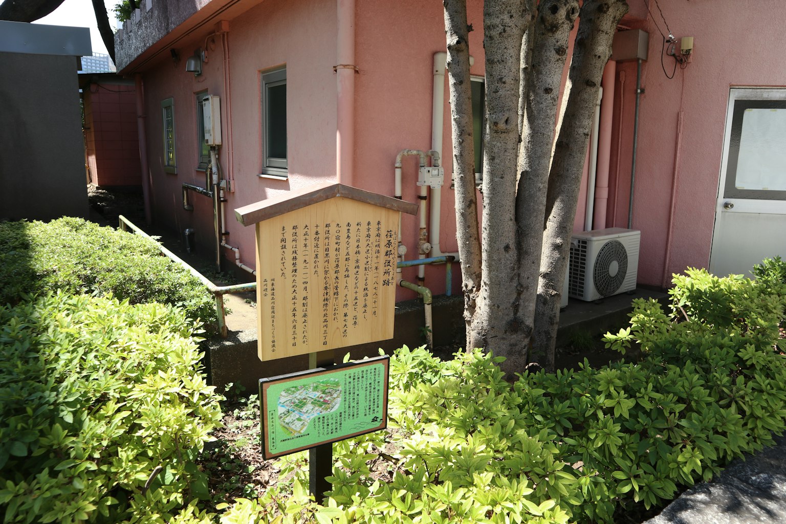 在粉紅色建築旁綠色植物和樹木之間的標牌