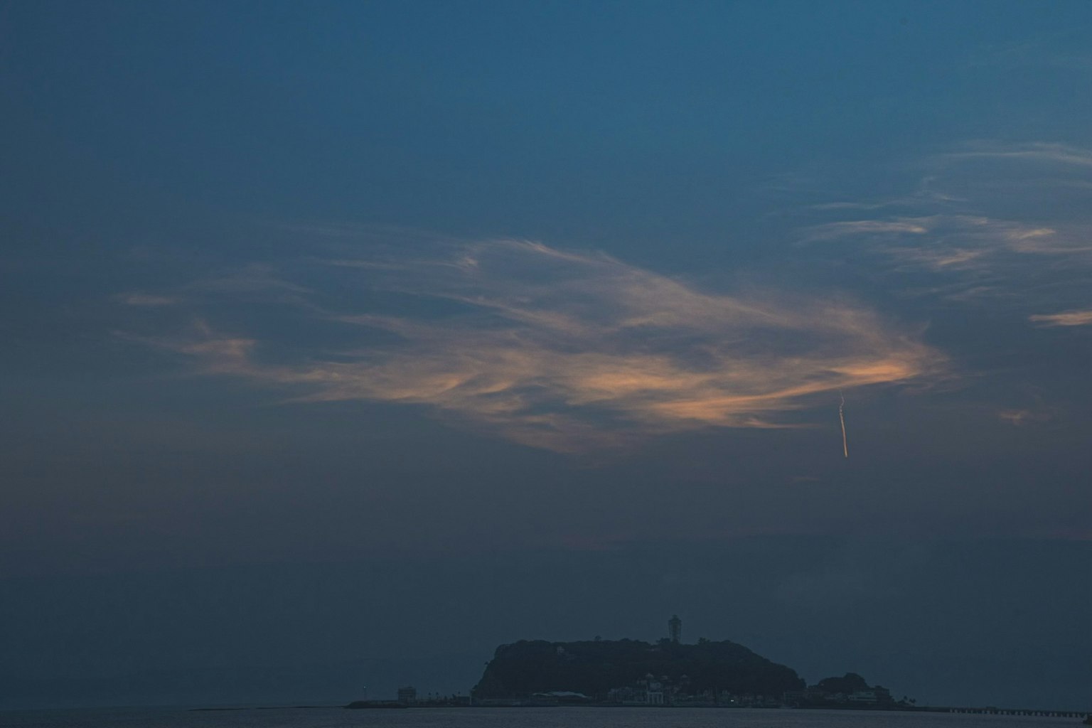 Una piccola isola silhouettata contro un cielo blu con nuvole al crepuscolo