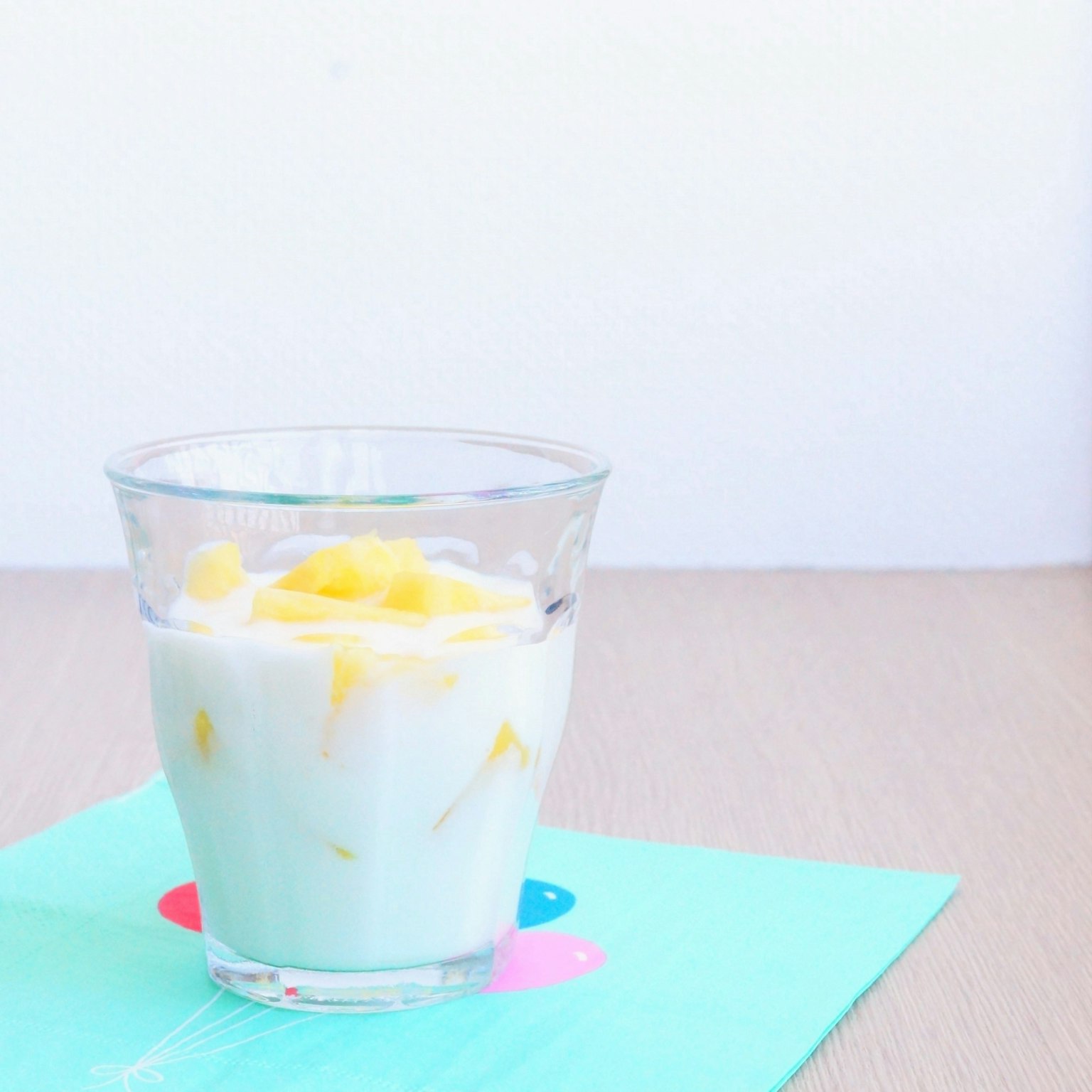 A clear glass with mango yogurt on a blue tablecloth