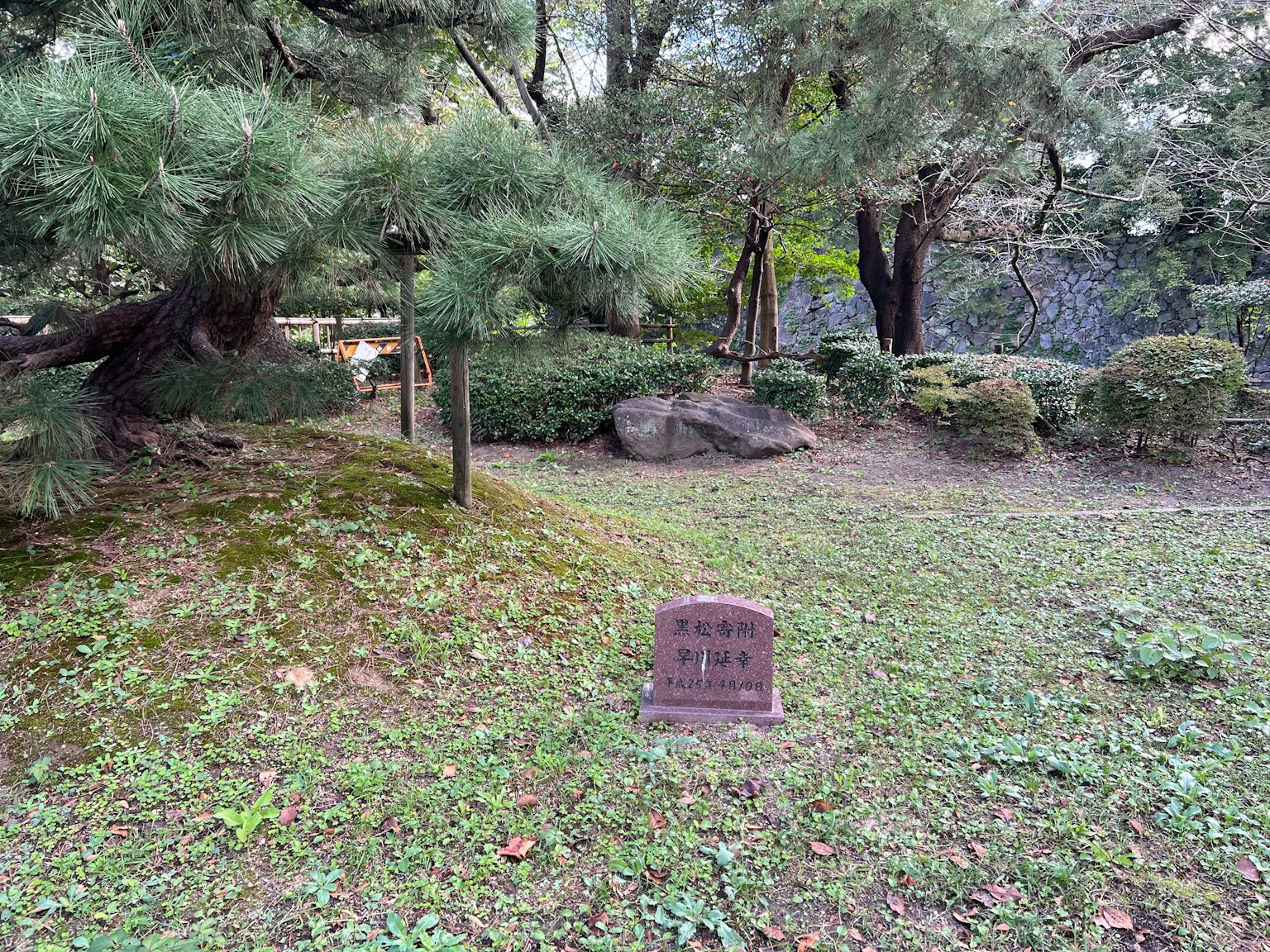 Monumento in pietra in un giardino lussureggiante circondato da alberi