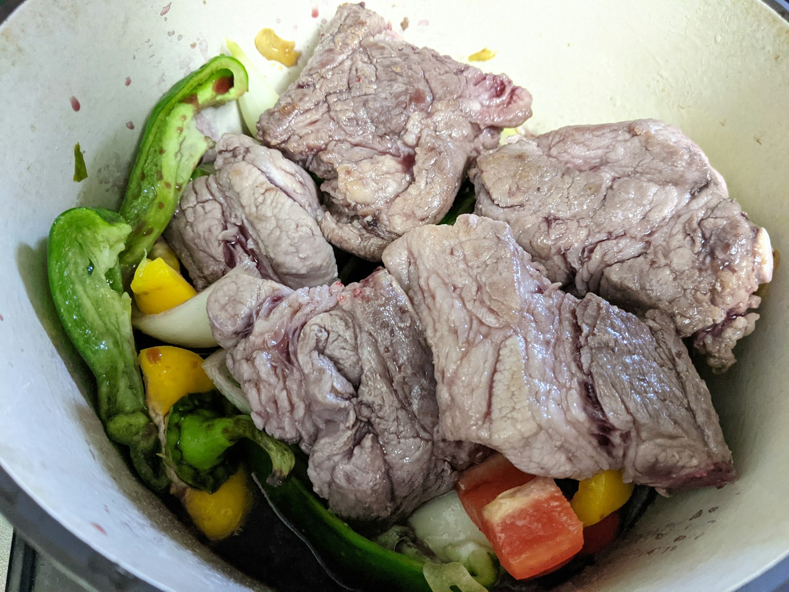 Morceaux de viande dans une casserole avec des légumes verts et jaunes