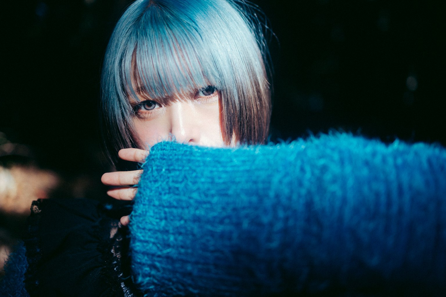 一位蓝发女性穿着蓝色毛衣，营造出神秘的氛围