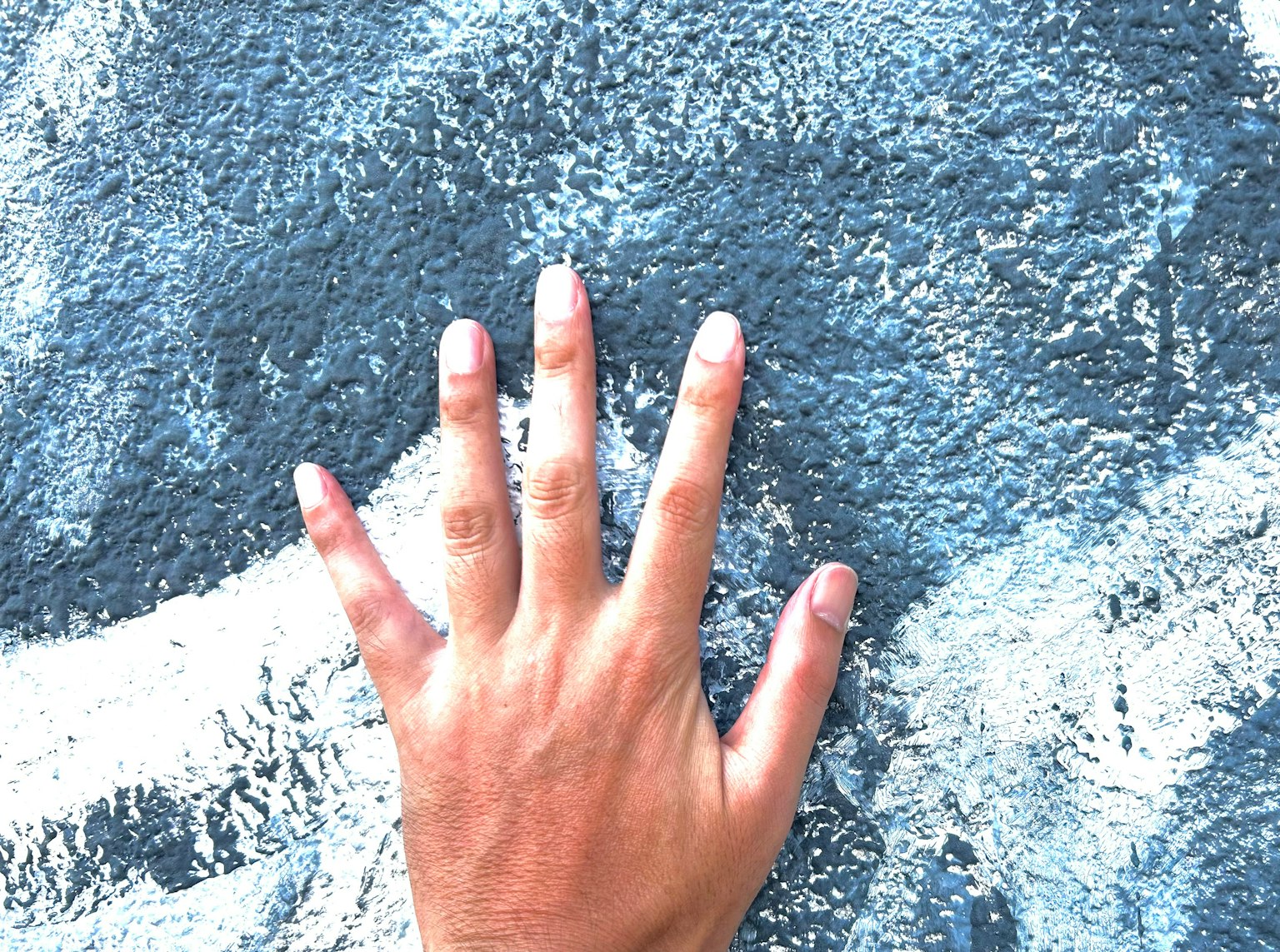 Eine Hand berührt eine strukturierte blaue Wand