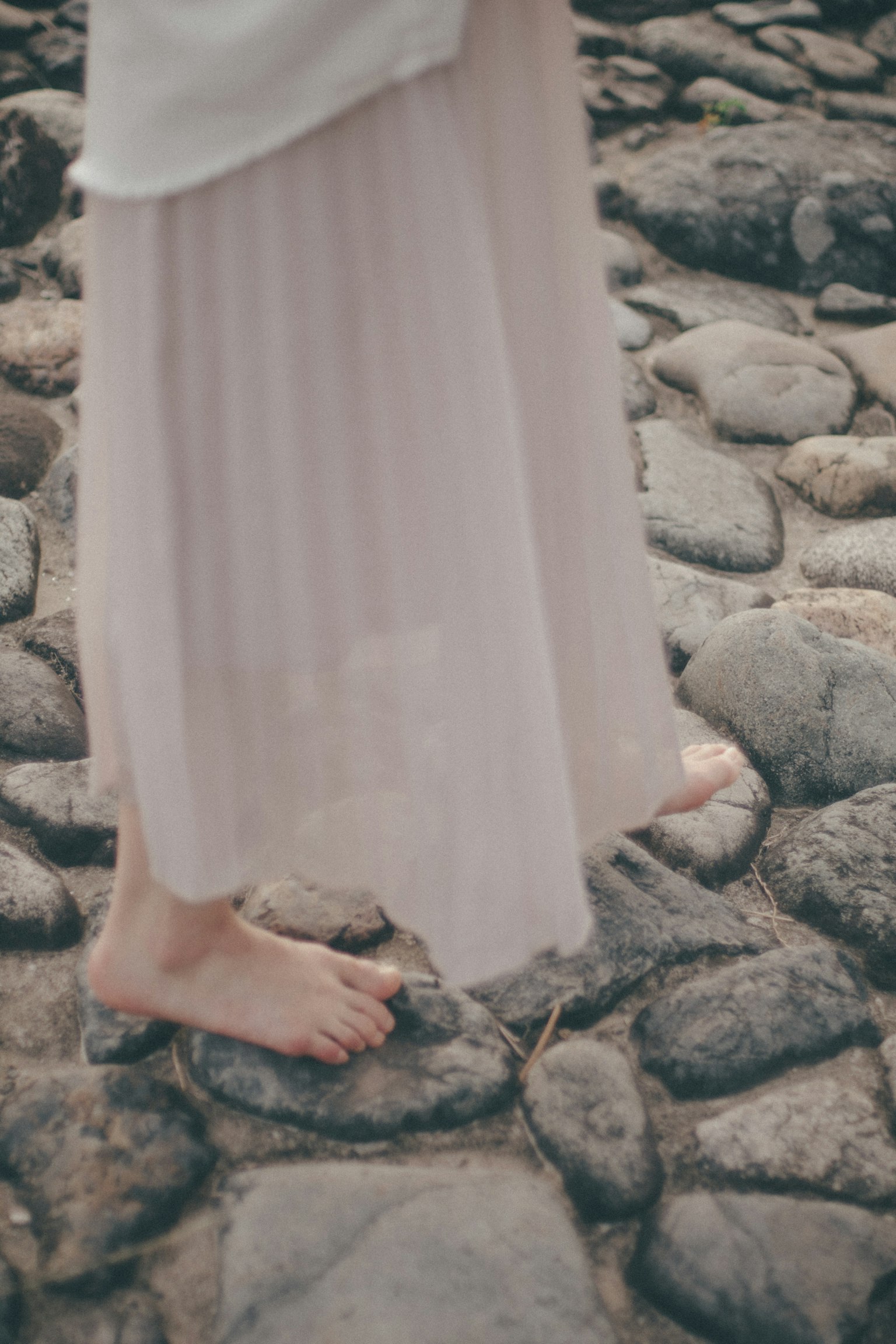 Des pieds nus d'une femme sur des pierres avec une jupe légère et fluide