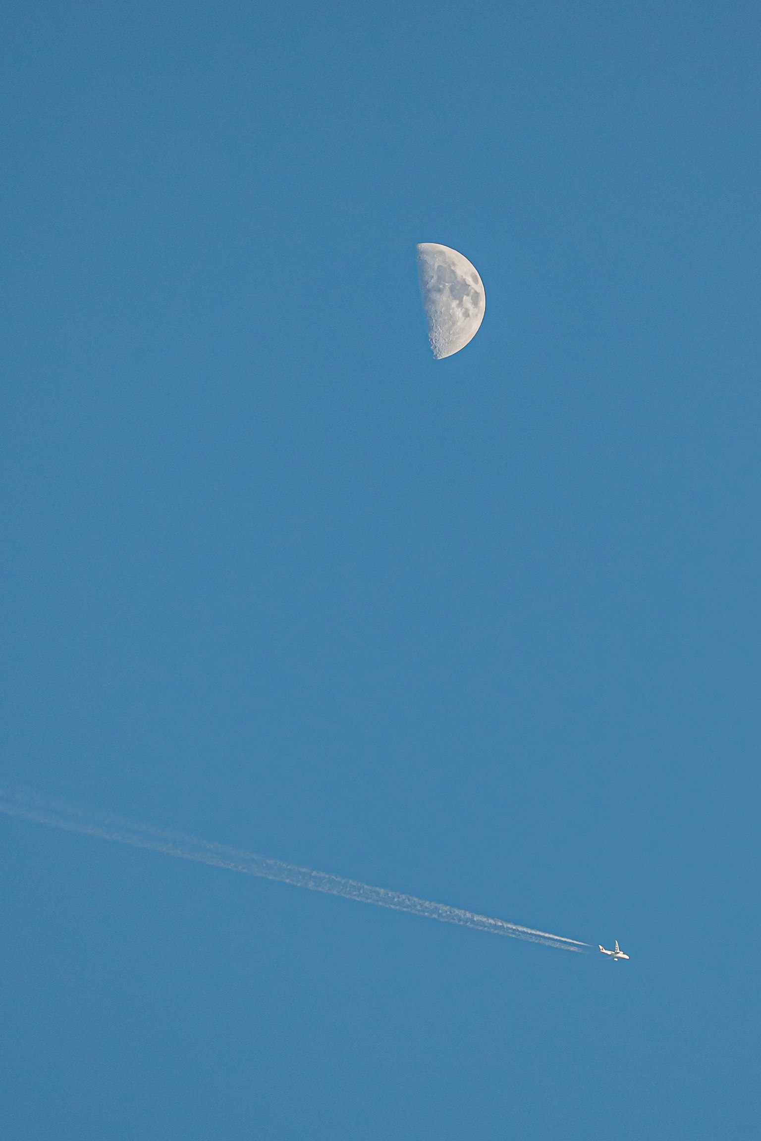Lune dans le ciel bleu avec une traînée d'avion