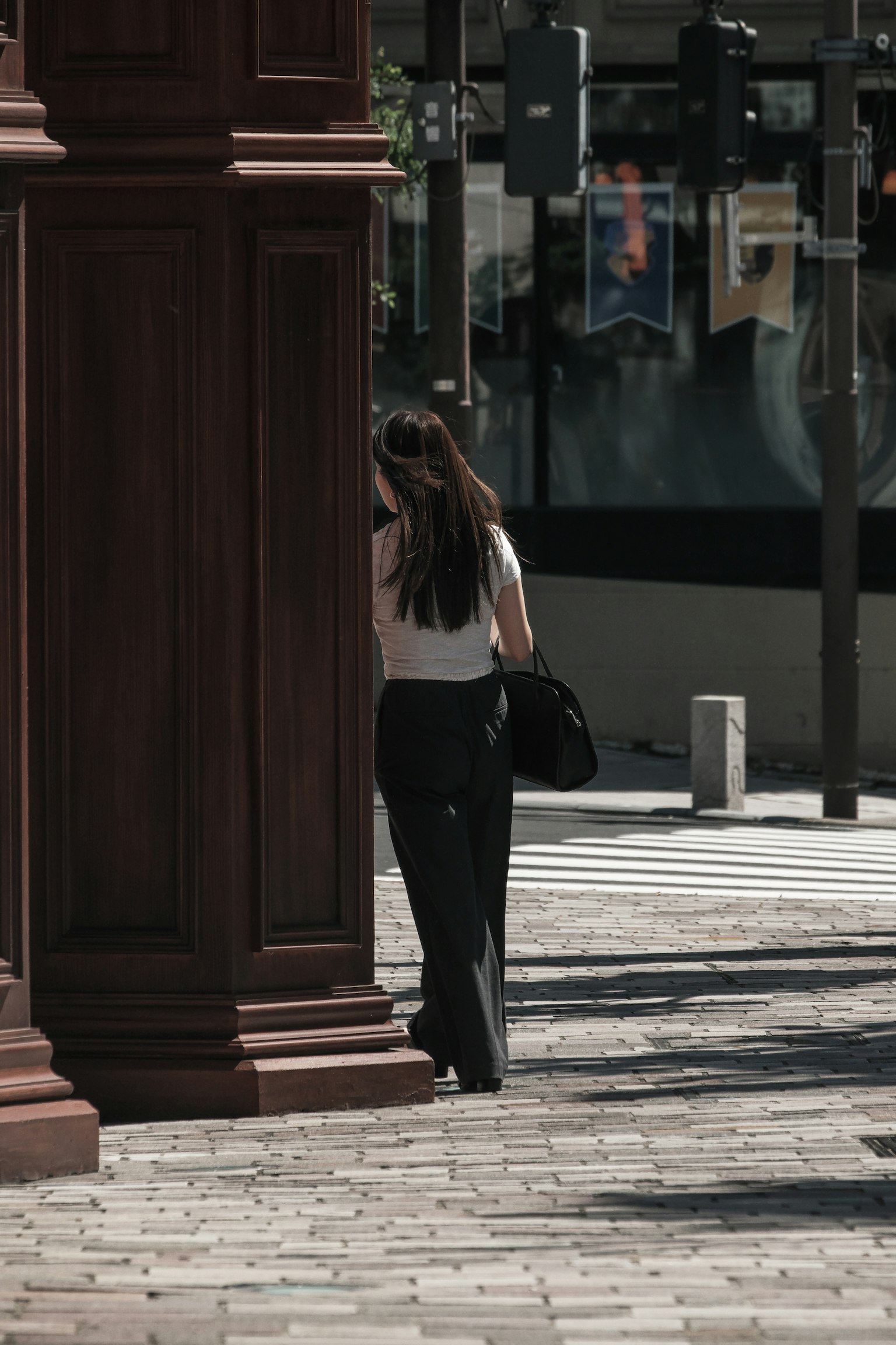 Eine Frau steht hinter einer Säule in einer städtischen Umgebung