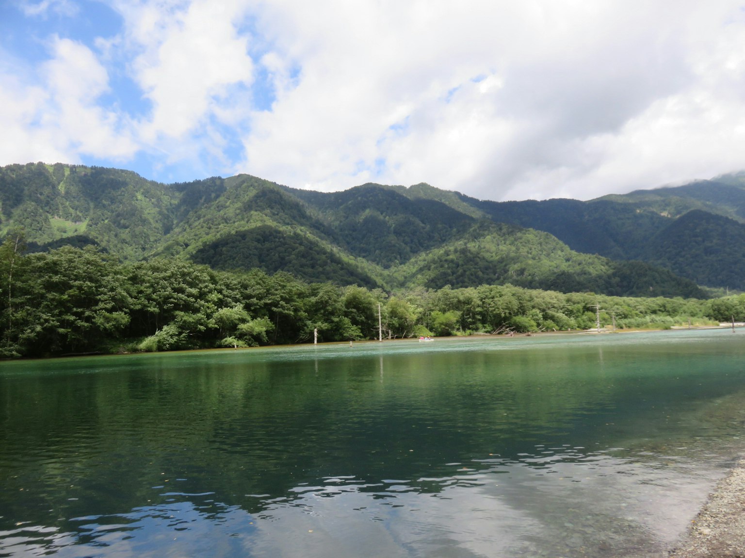 Pemandangan danau tenang dengan pegunungan di latar belakang