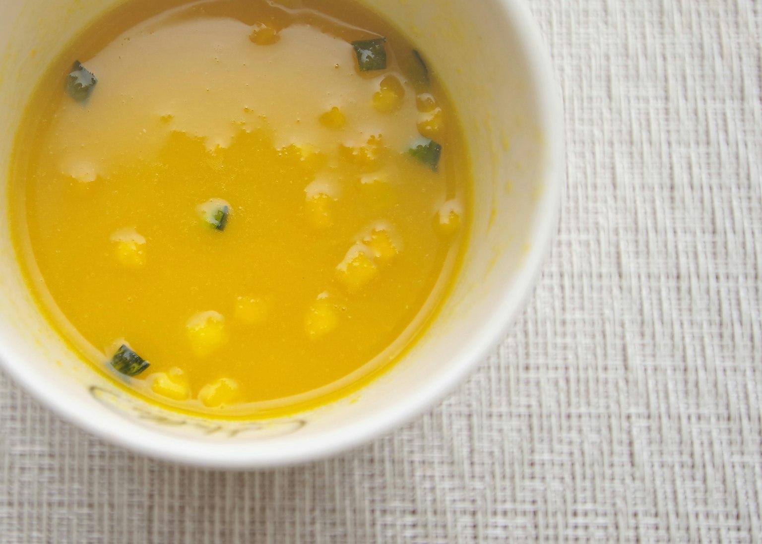 Soupe jaune avec du maïs et des herbes vertes visibles