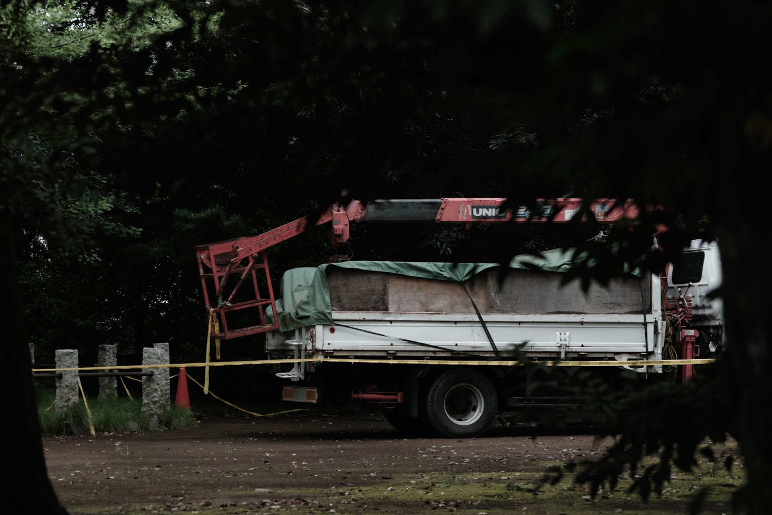 Ein weißer Lastwagen mit einem roten Kran, der in einem Waldgebiet geparkt ist
