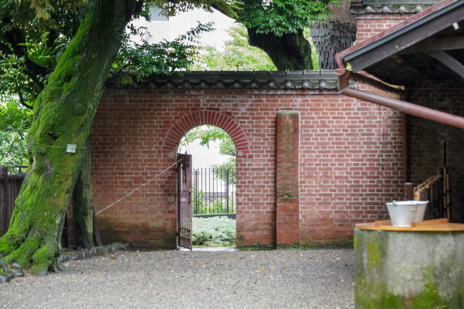 Arco di mattoni circondato da alberi che conduce a un giardino