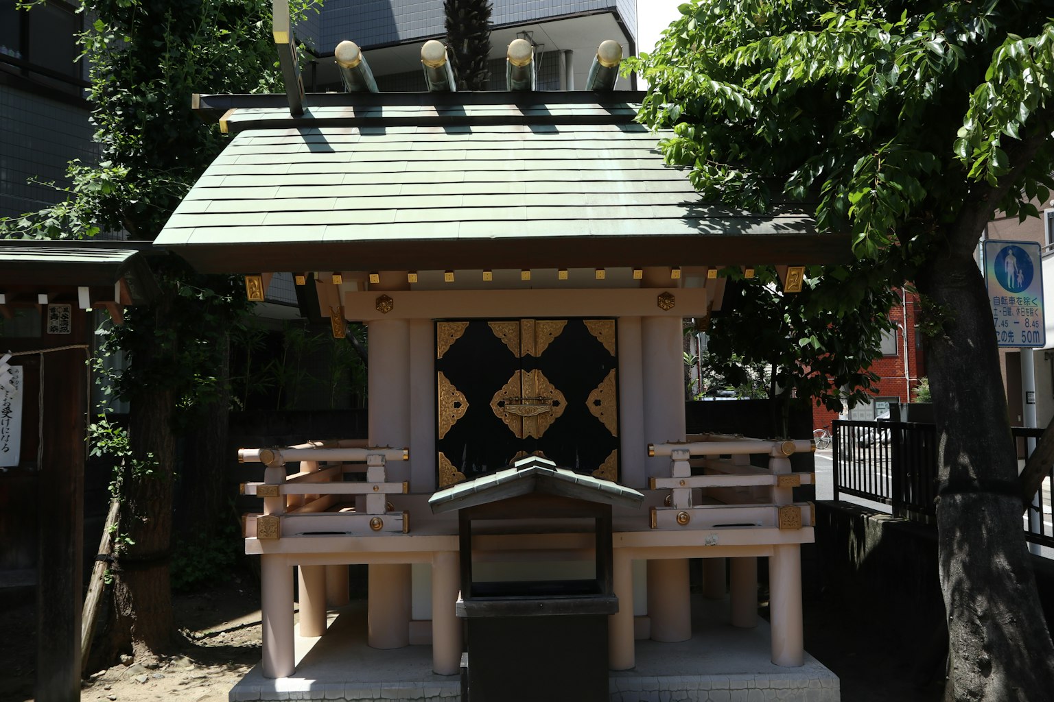 Small shrine building with a green roof and wooden balcony features