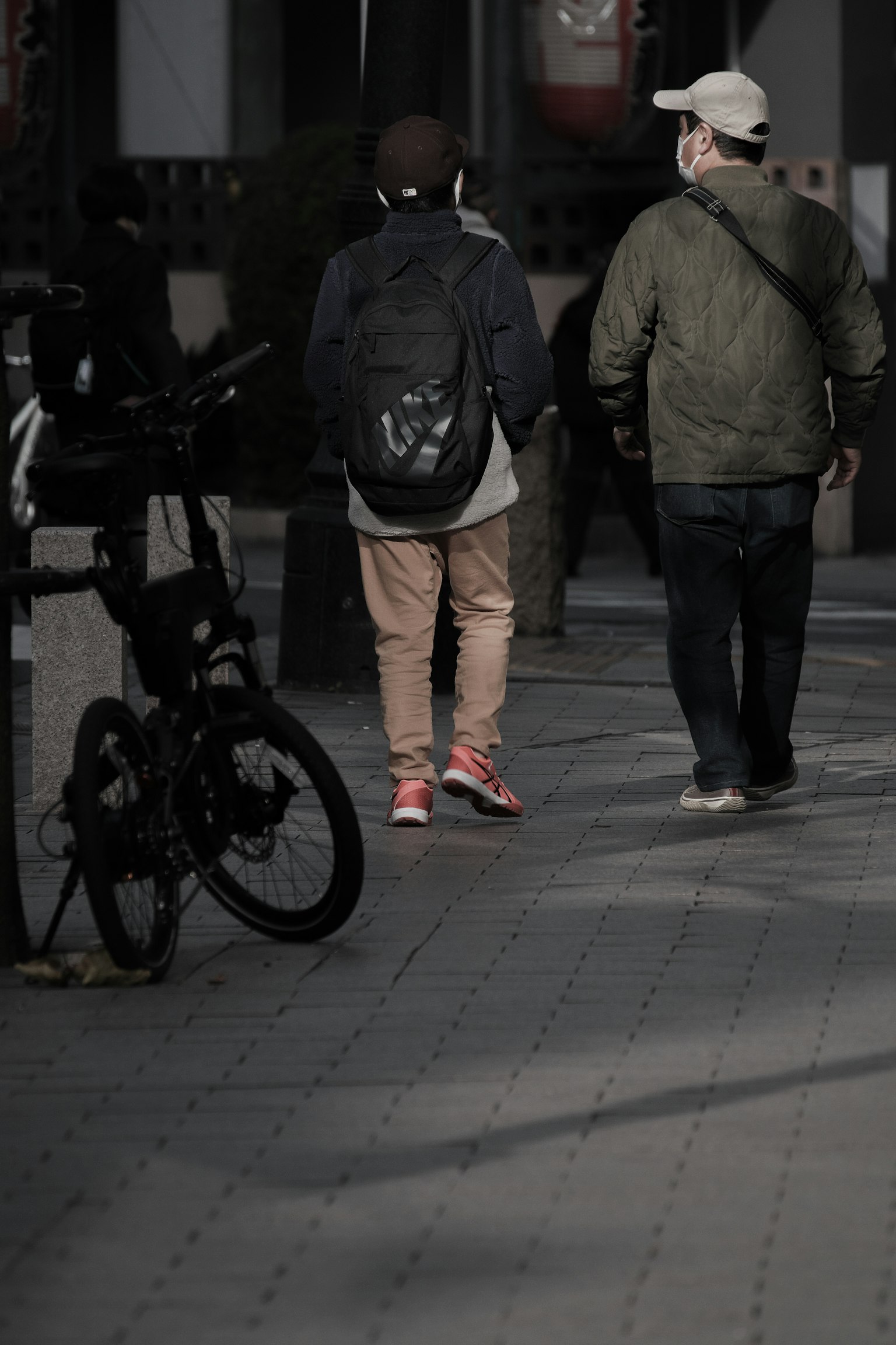 兩名男子在城市街道上行走，附近有一輛自行車