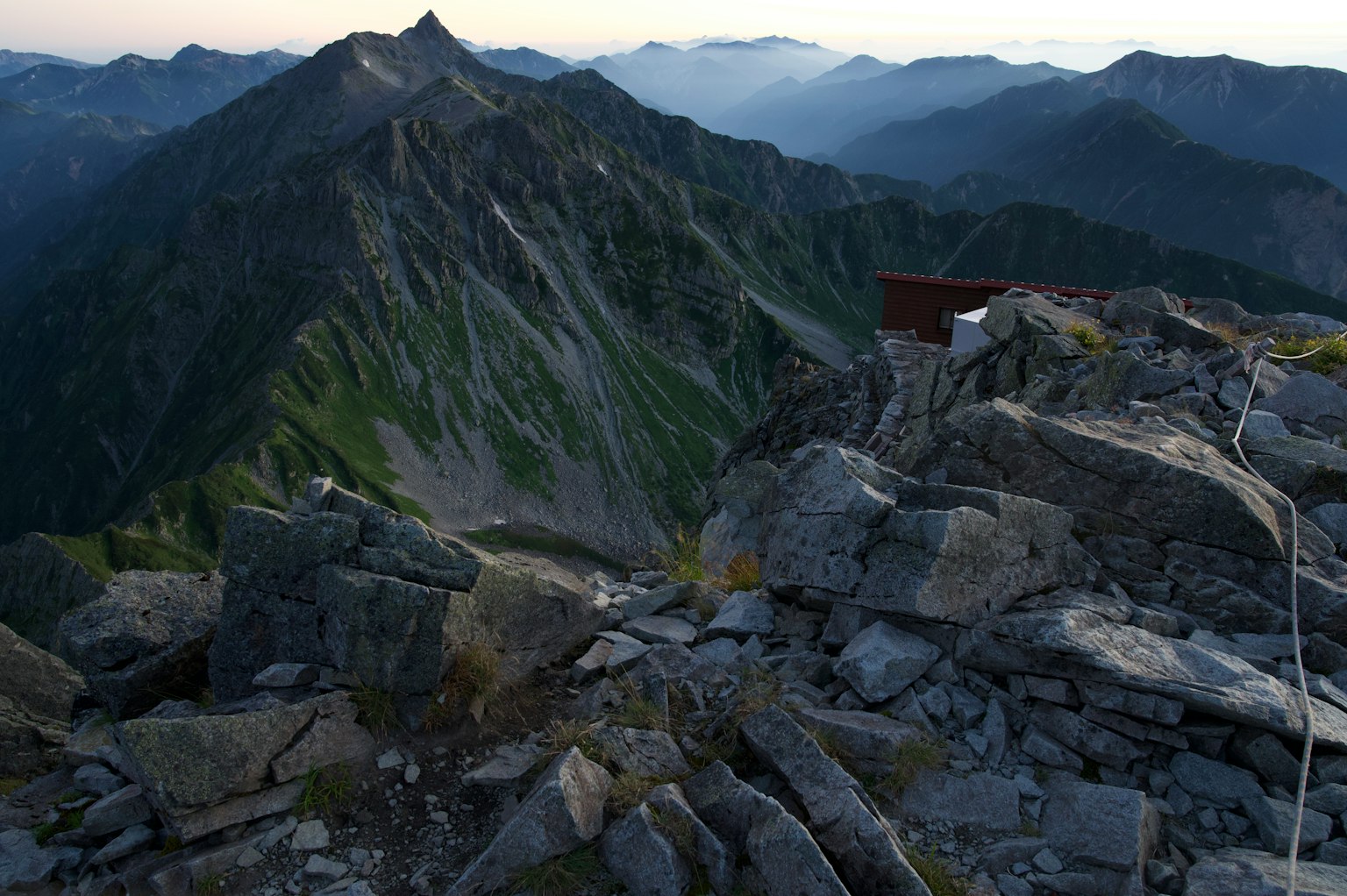View from the mountain summit rocky terrain green slopes and distant mountains