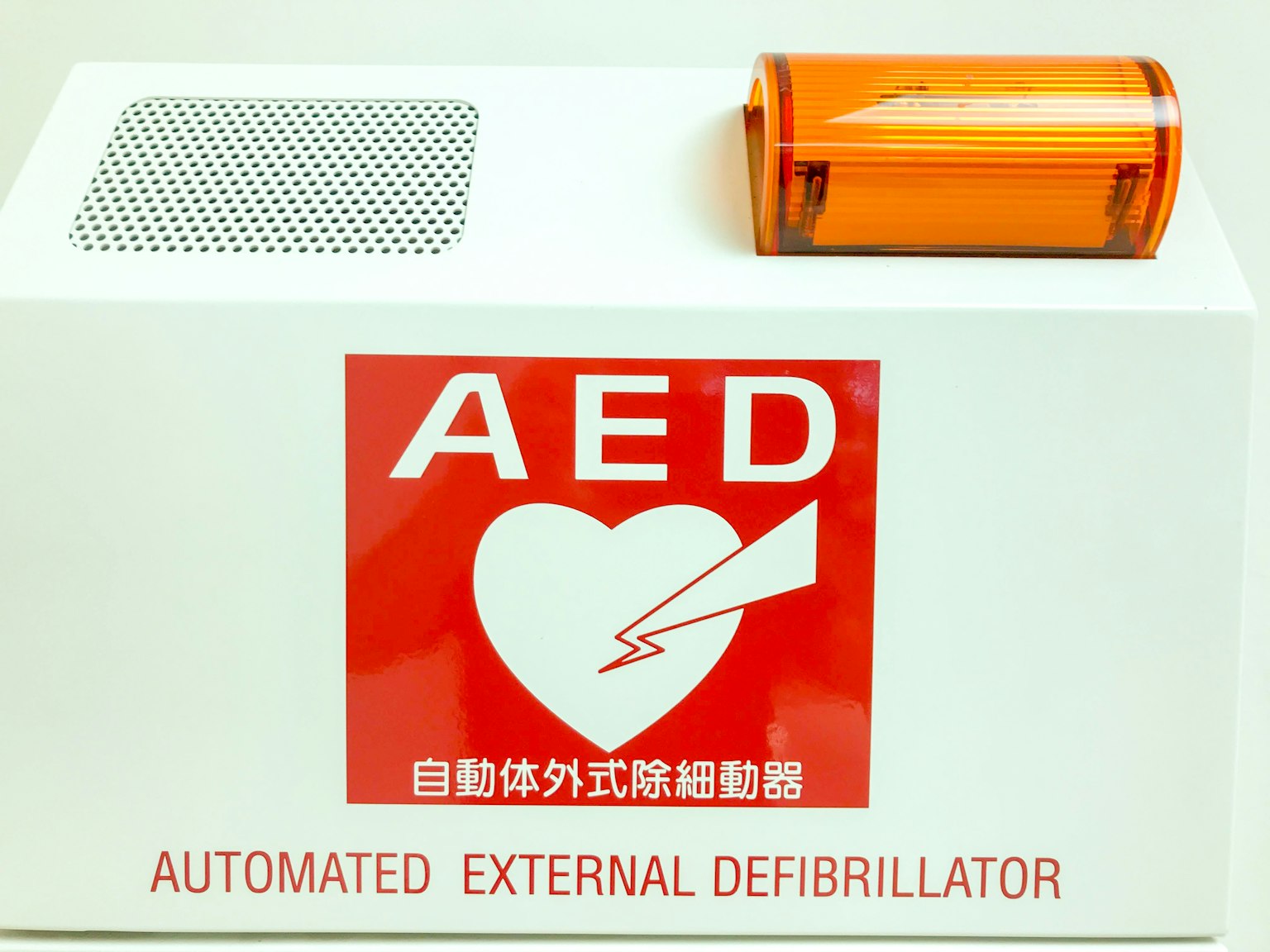 Defibrillator Eksternal Otomatis dengan logo merah dan penutup oranye