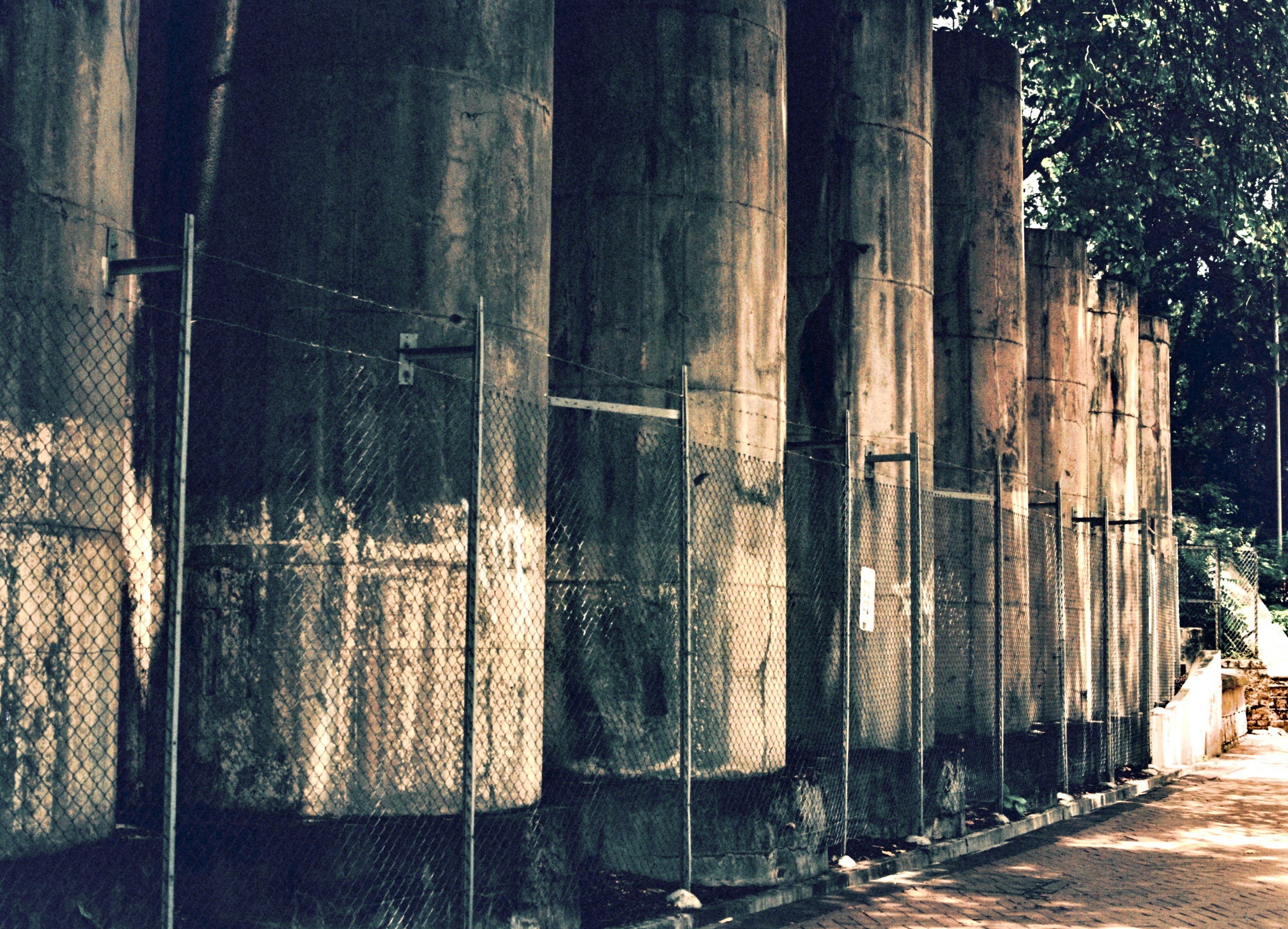 gang dengan dinding beton dan pagar kawat berduri