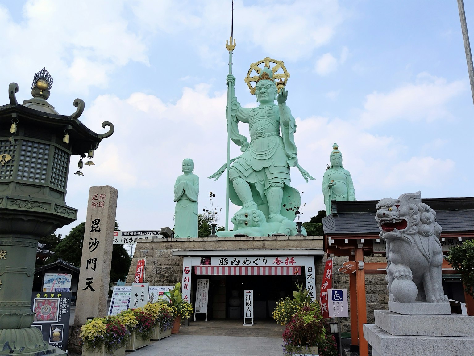 Entrance of a shrine featuring a large bronze deity statue surrounded by stone figures
