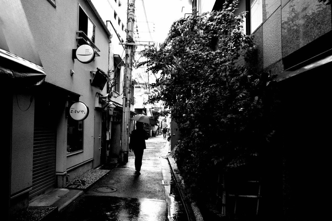 路地の濡れた石畳と街灯のある商店街の通り