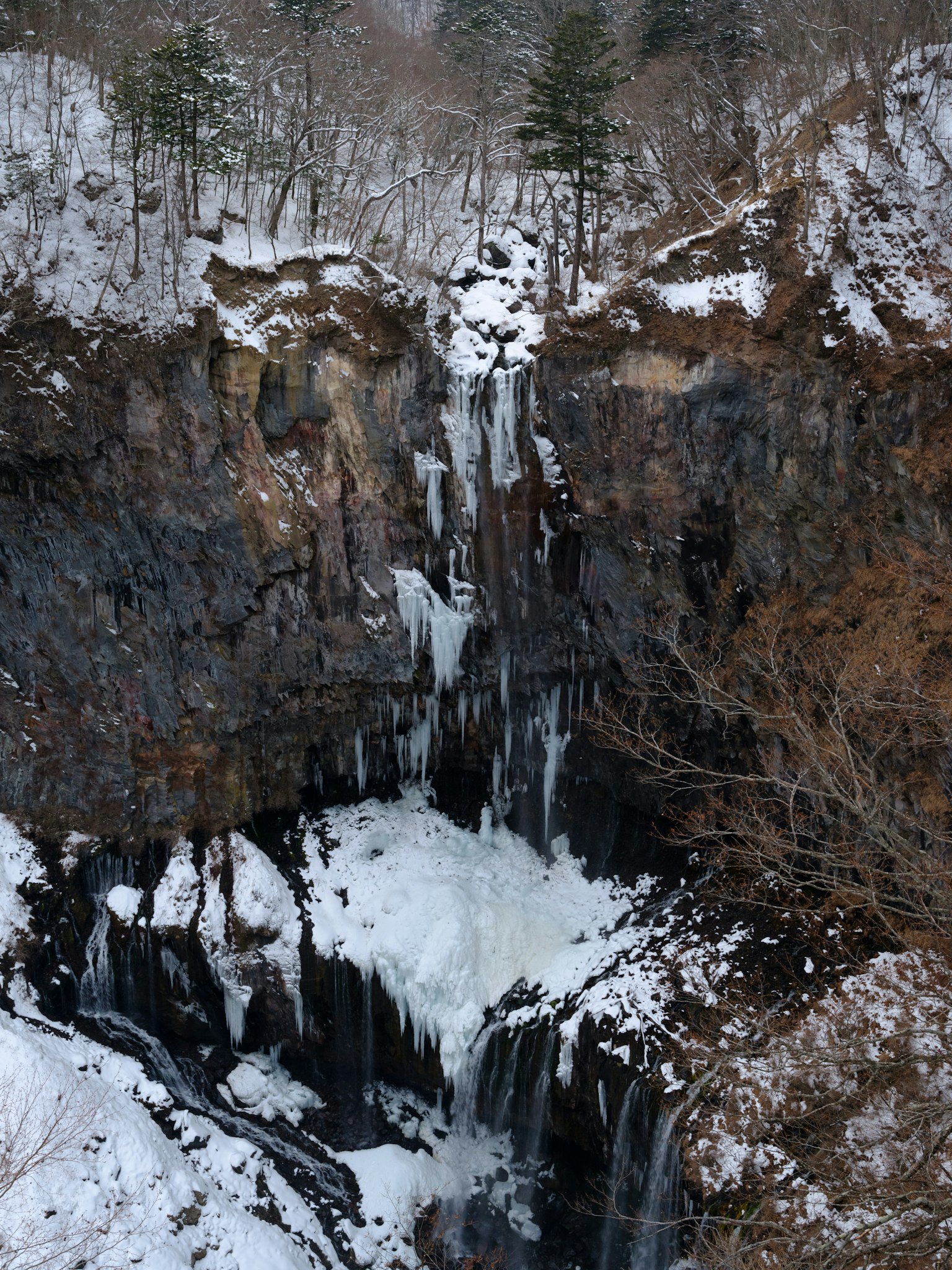 Un paisaje invernal con una cascada que cae sobre rocas rodeadas de nieve