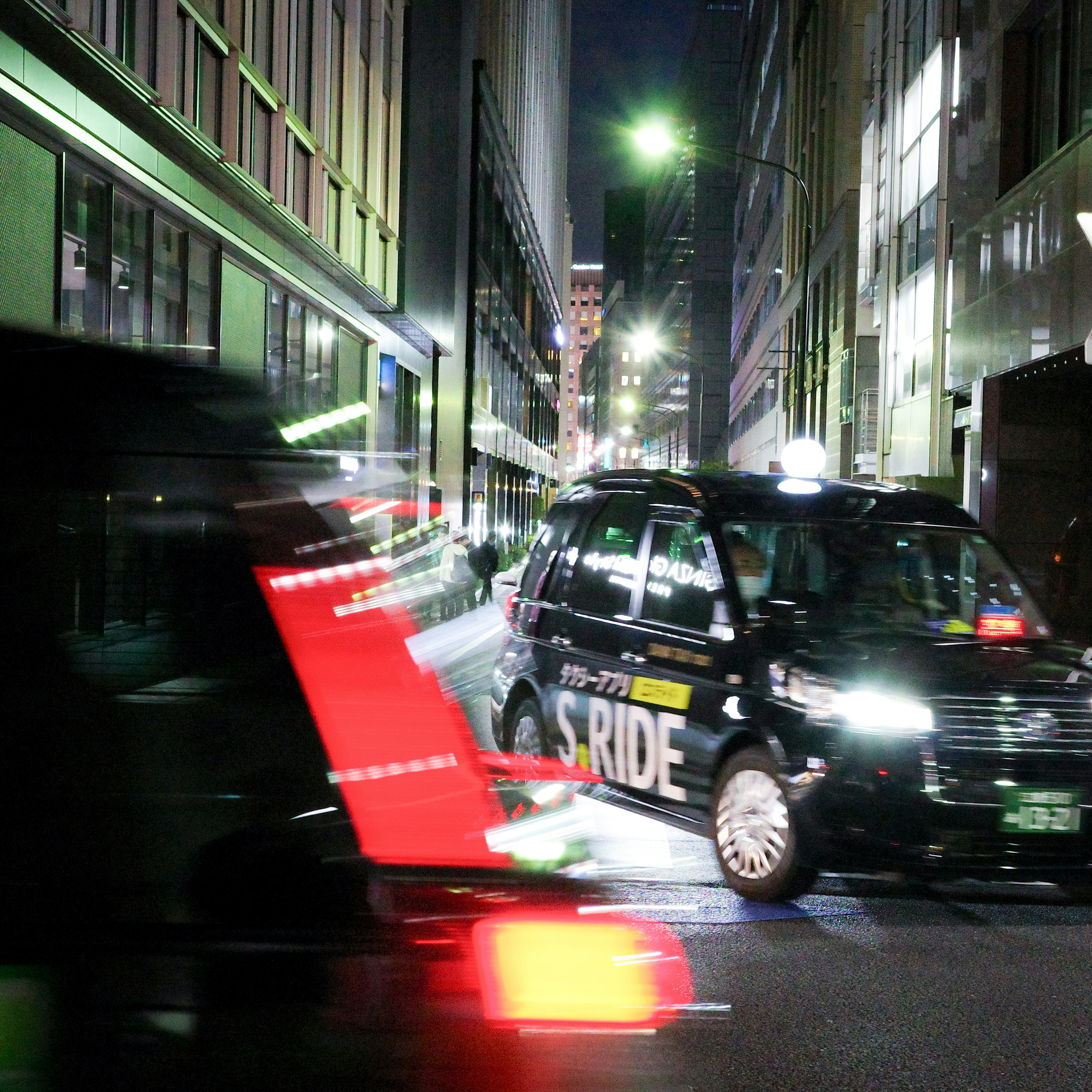 夜の東京の路地を走るタクシーと残像の光