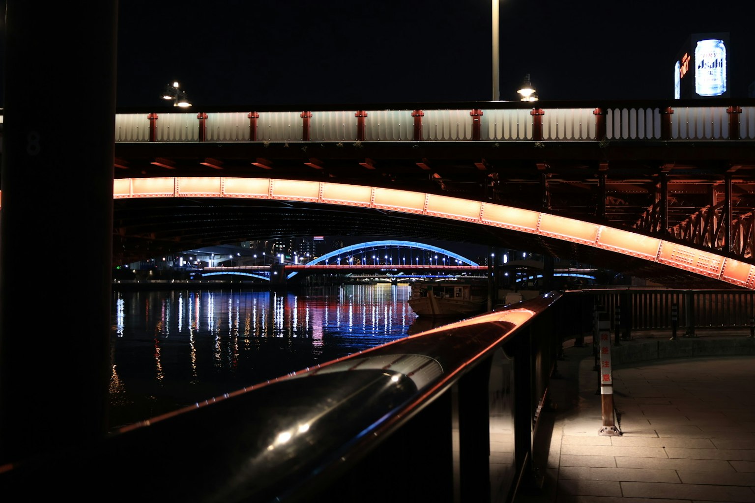Imagen de un hermoso puente sobre un río de noche con luces brillantes y reflejos
