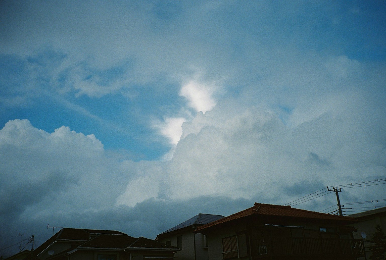 Cielo con tonalità di blu e nuvole bianche silhouette di case in primo piano