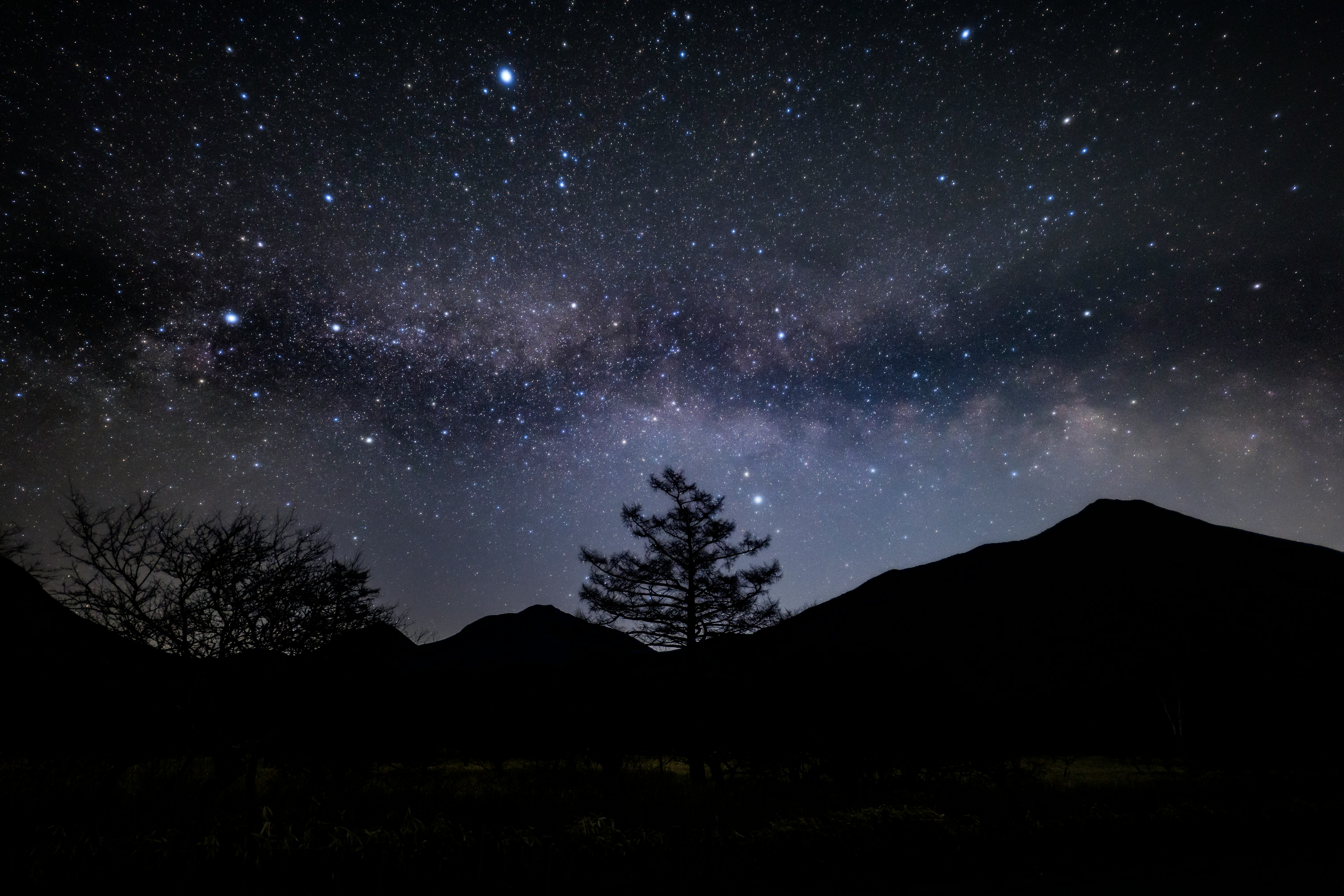 夜空に広がる天の川と星、山のシルエット