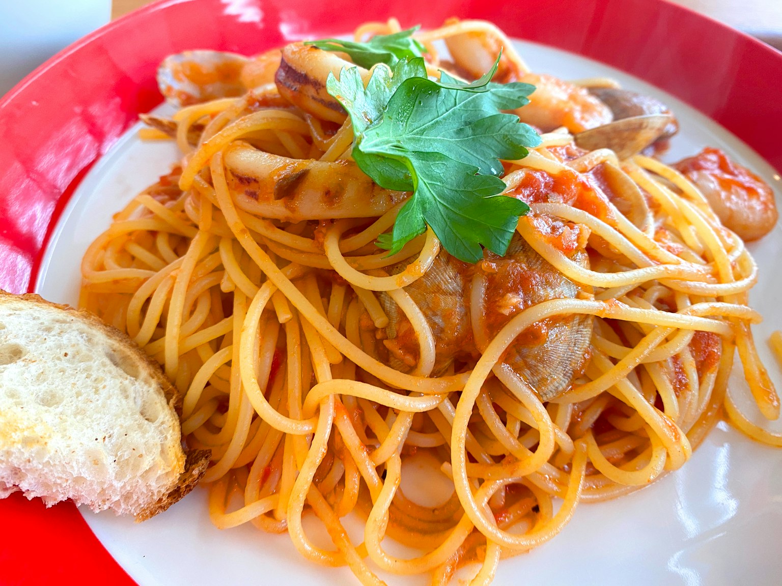 Assiette de spaghetti aux fruits de mer garnie d'herbes fraîches servie avec une tranche de pain