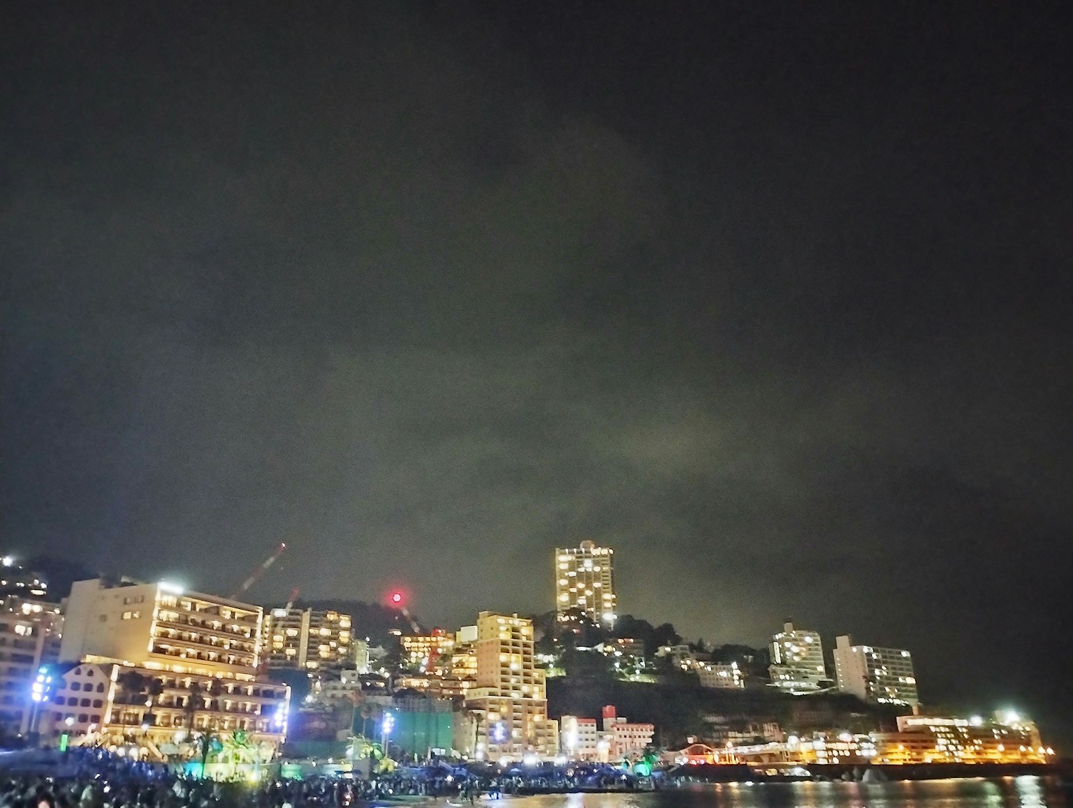 Línea de horizonte de la ciudad iluminada por la noche con luces de colores y cielo nublado