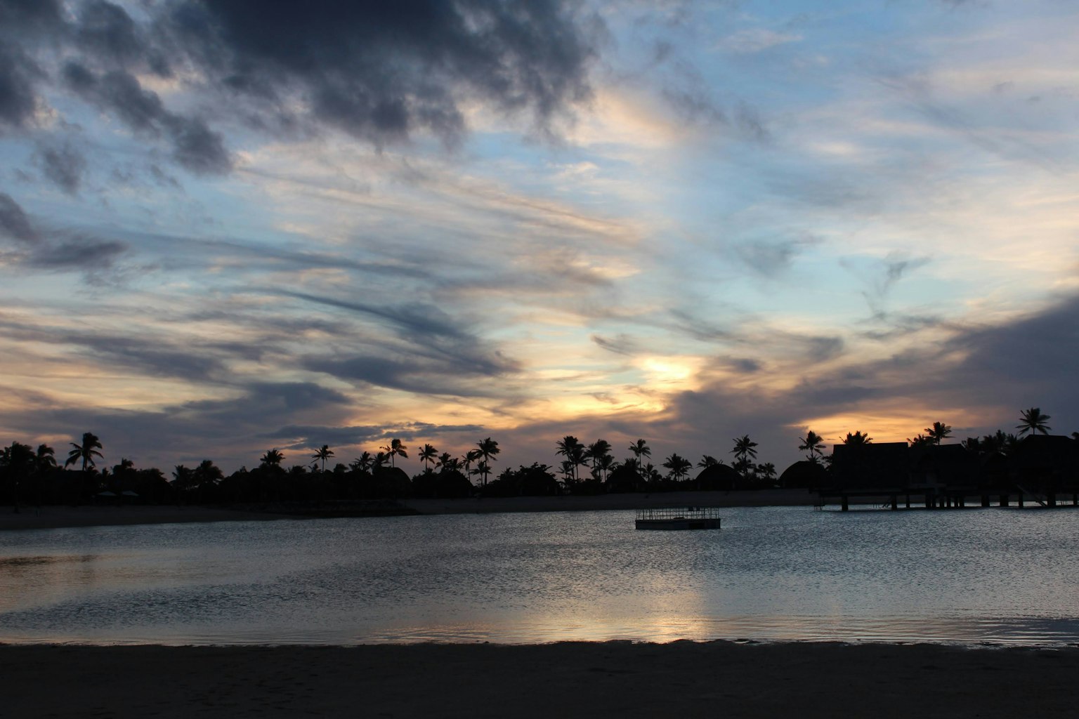 Magnifique ciel au coucher de soleil avec une surface d'eau tranquille silhouette de palmiers le long de la plage