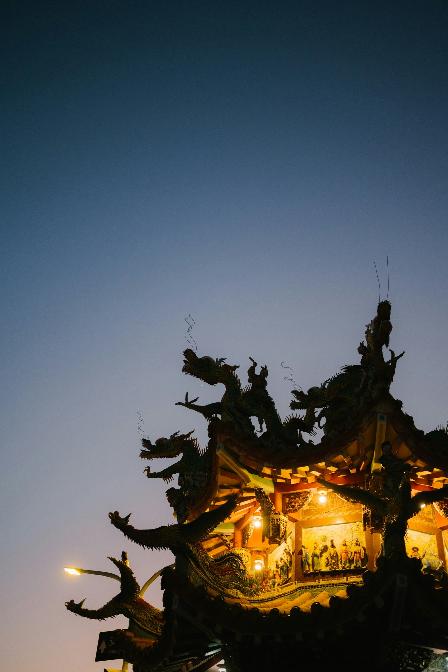 黃昏時分寺廟屋簷的龍雕與燈光