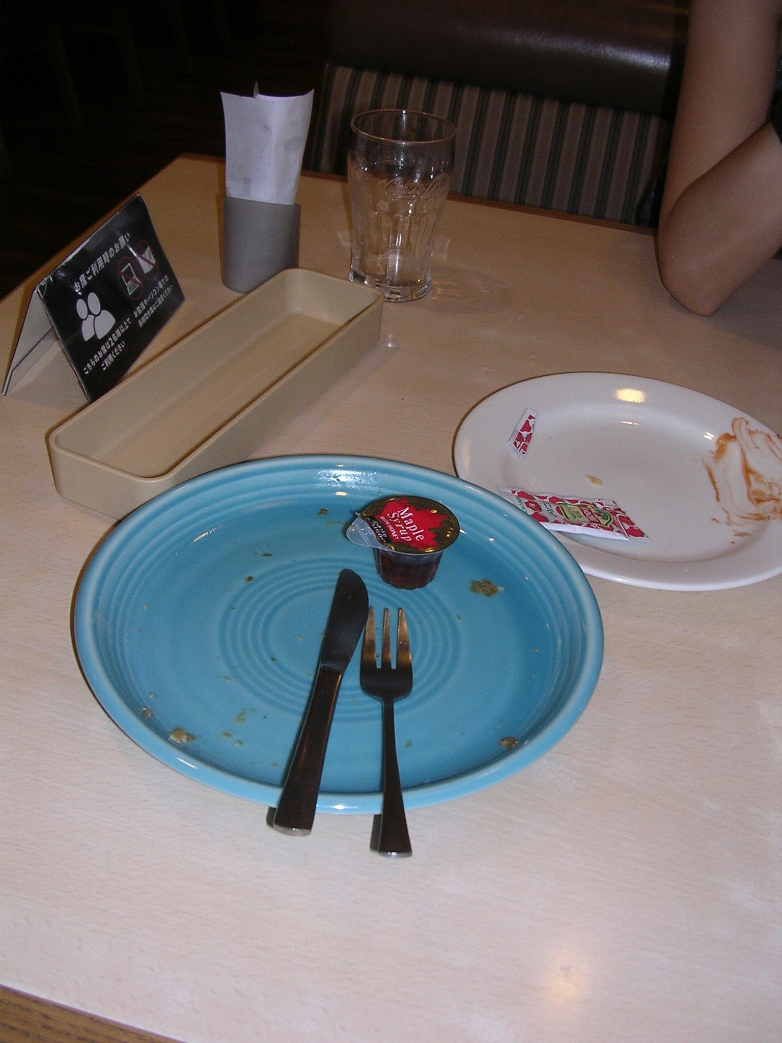 桌子上有一個藍色的盤子和一個小容器，盤子上有食物殘渣