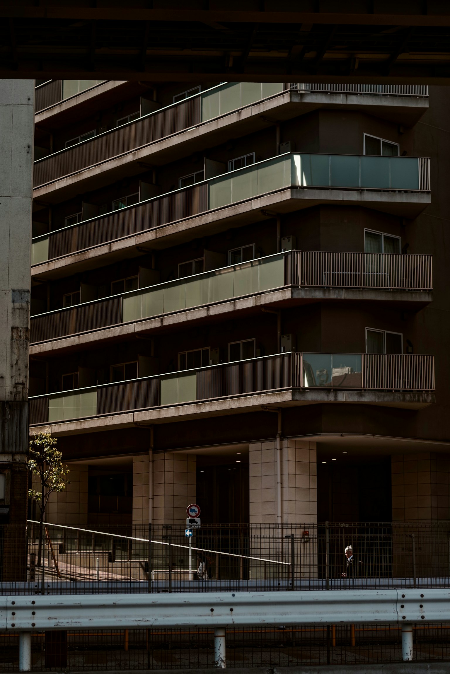 발코니와 녹지가 보이는 현대 아파트 건물 외관, 낮은 조명에서 촬영됨
