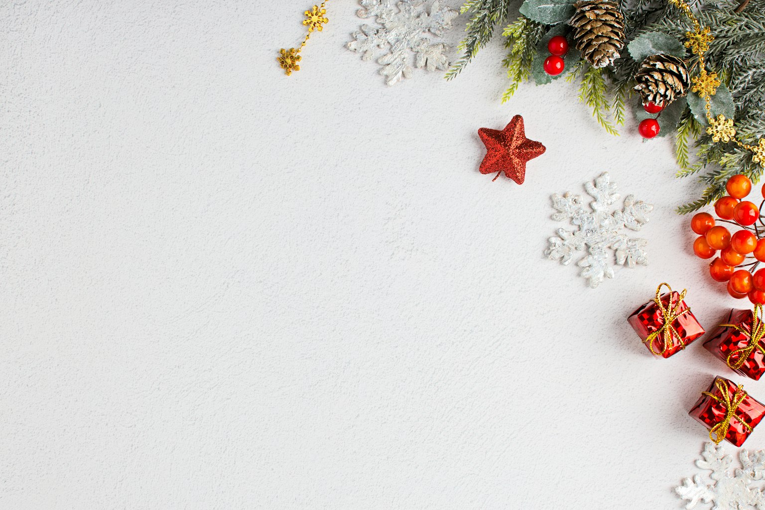 Decorazioni natalizie con pigne stella rossa e piccoli regali su sfondo bianco