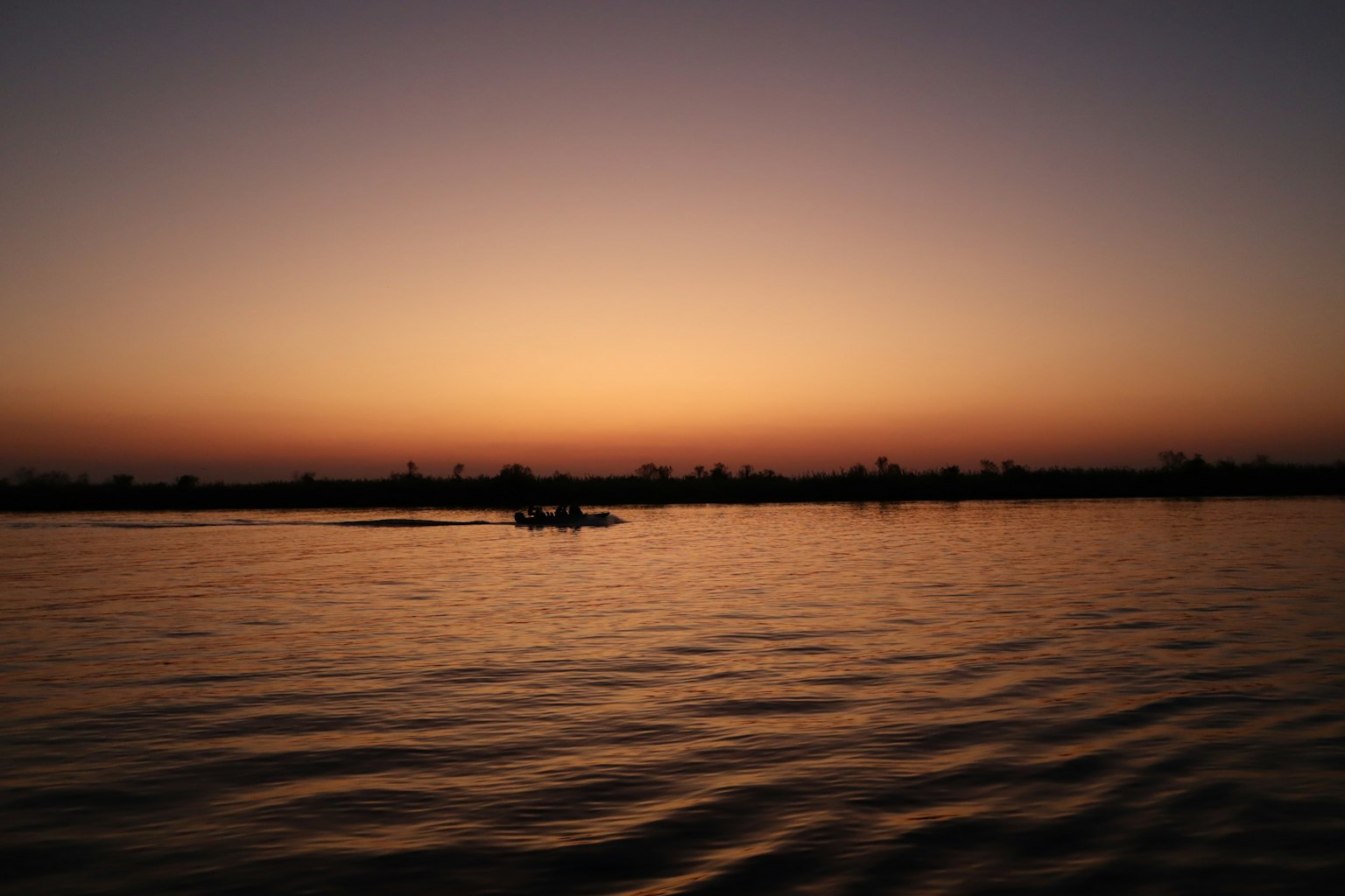 Serene sunset landscape with silhouette of boat on calm water