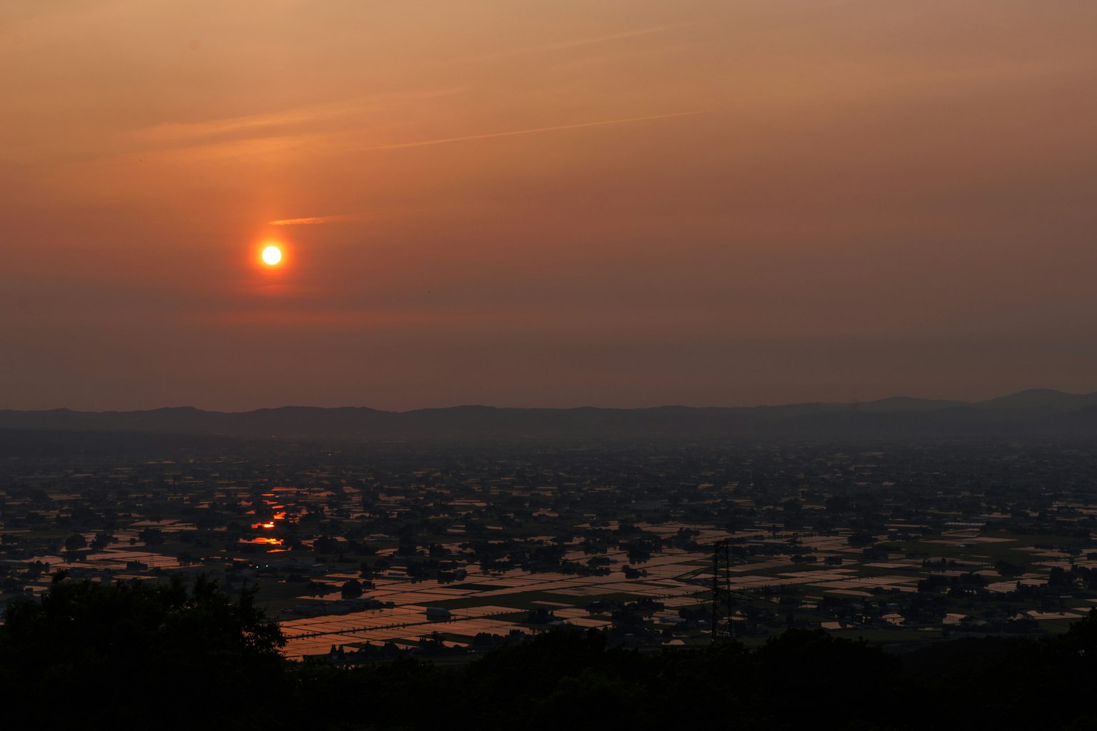 Vista panoramica del tramonto con riflessi sull'acqua e colline lontane
