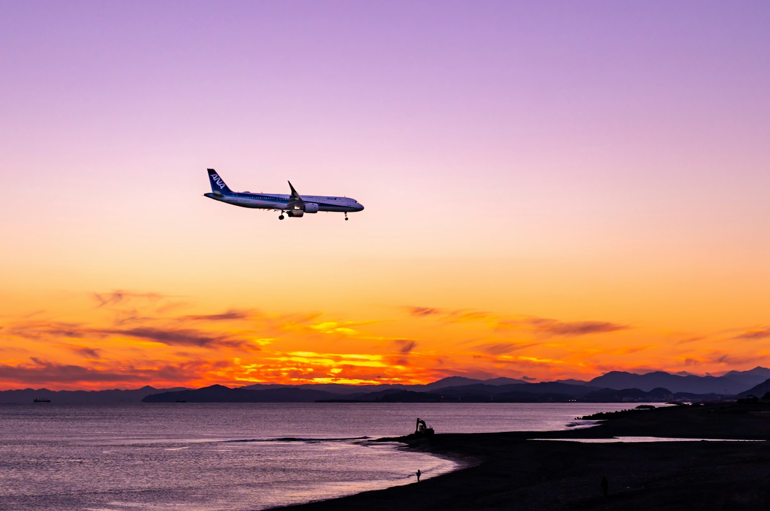Un avion atterrissant pendant un coucher de soleil vibrant sur l'océan