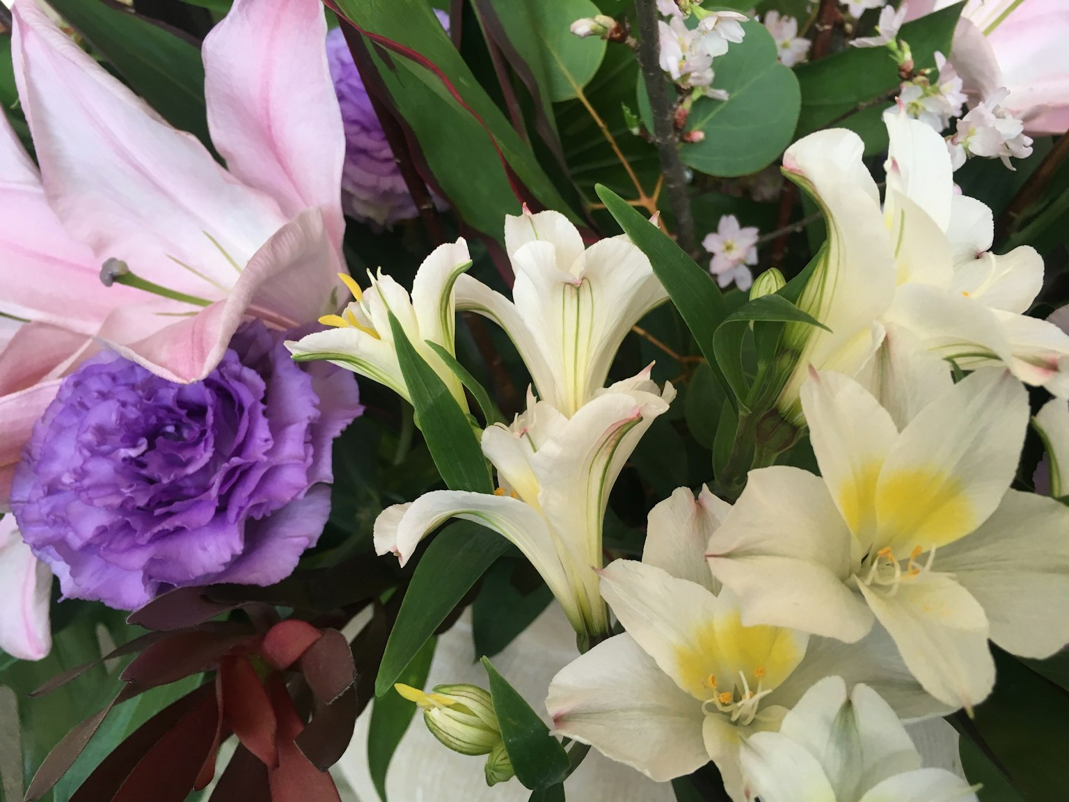 Bunte Blumenarrangement mit weißen Lilien und lila Rosen